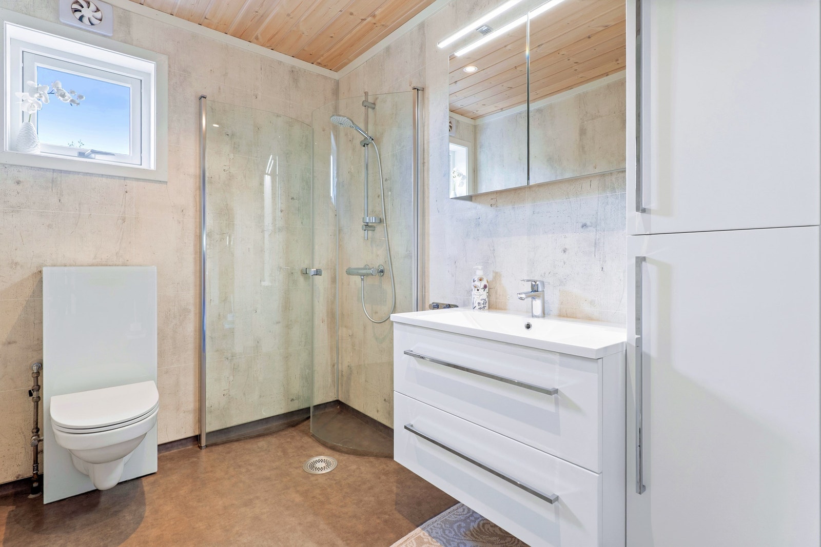 Bad ved soverom med moderne baderomsplater, elektriske varmekabler og godt med oppbevaringsplass. Galleribilde