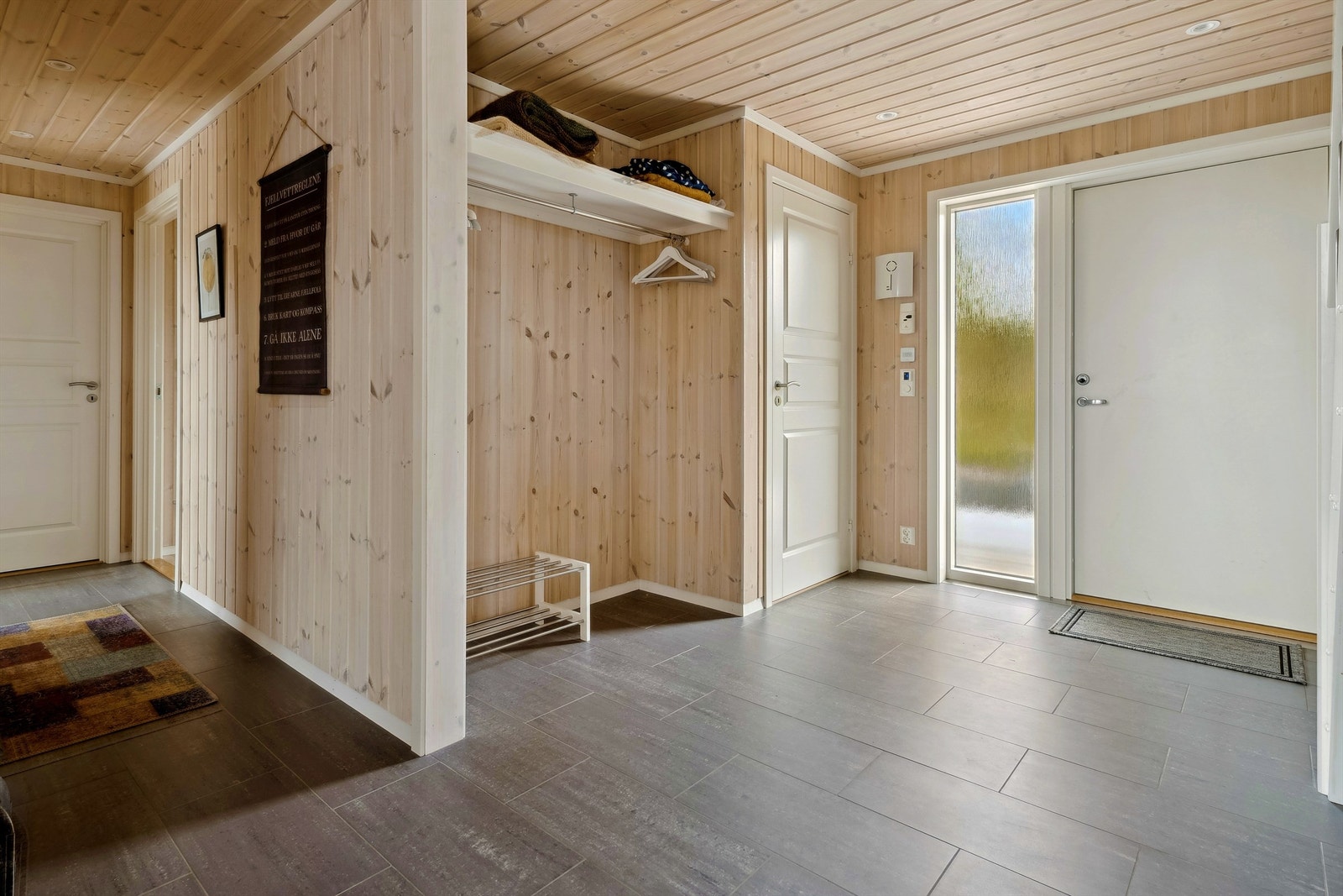 Romslig entré med god garderobeplass og fliser på gulvet. Galleribilde