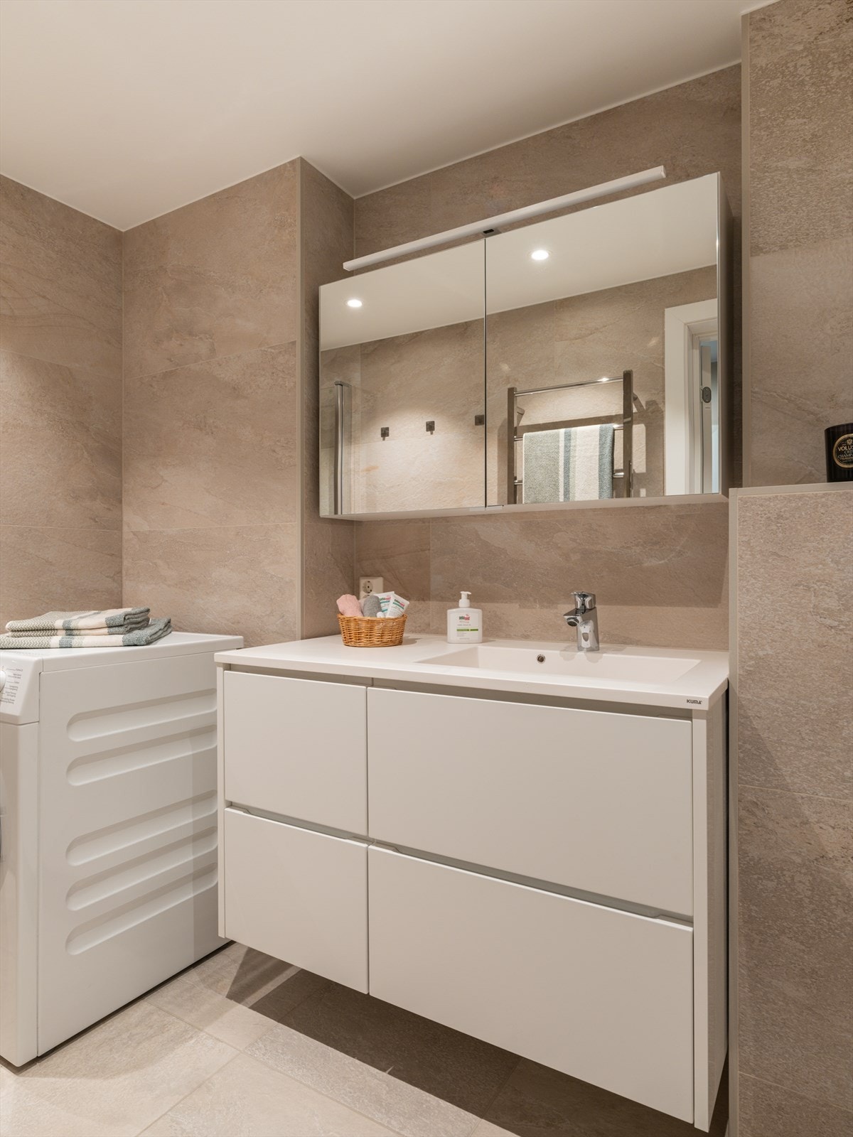 Innredningen inkluderer en servant med skuffer, speilskap og vegghengt toalett med innebygget sisterne. Galleribilde