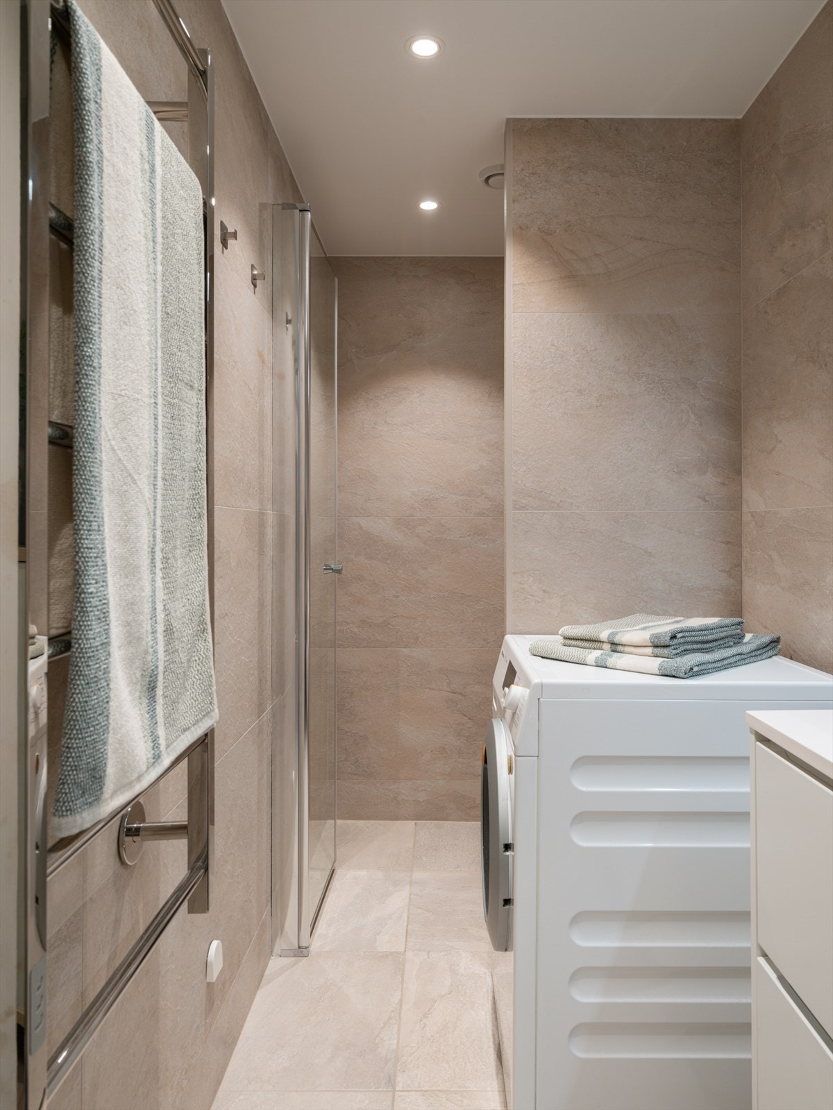 Badet er flislagt med delikate, storformat fliser på både gulv og vegger. Galleribilde