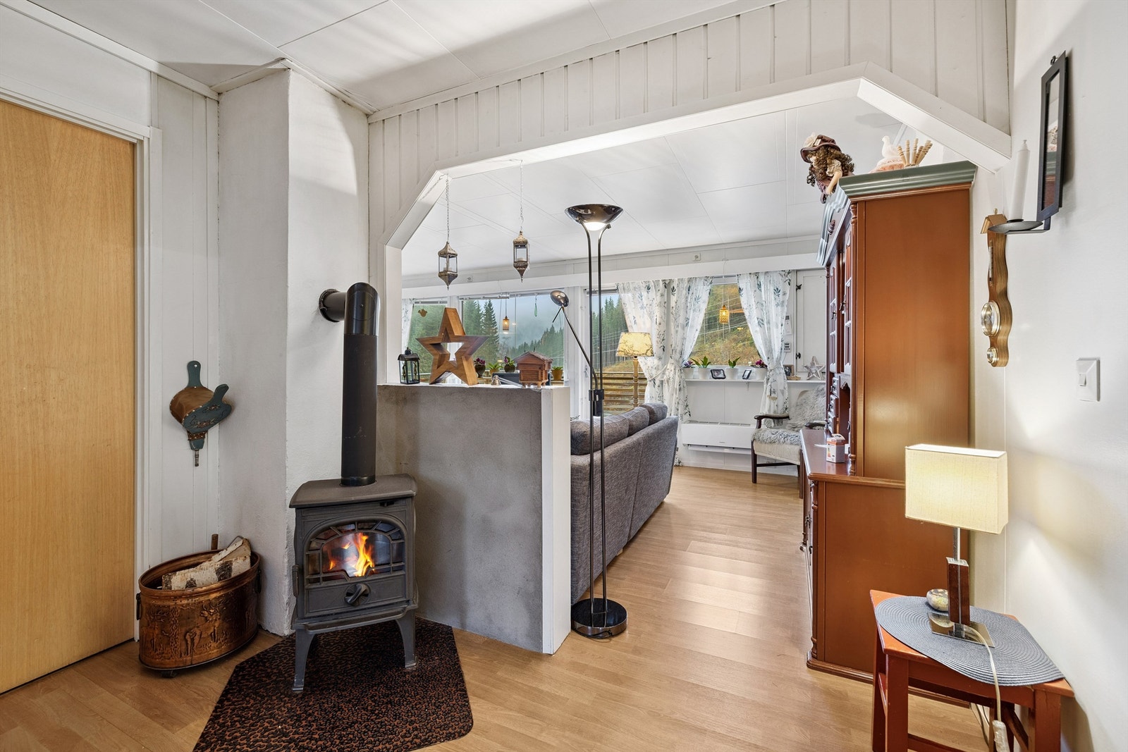 Vi beveger oss over til kårboligen, som har en lys stue med vedovn. Galleribilde