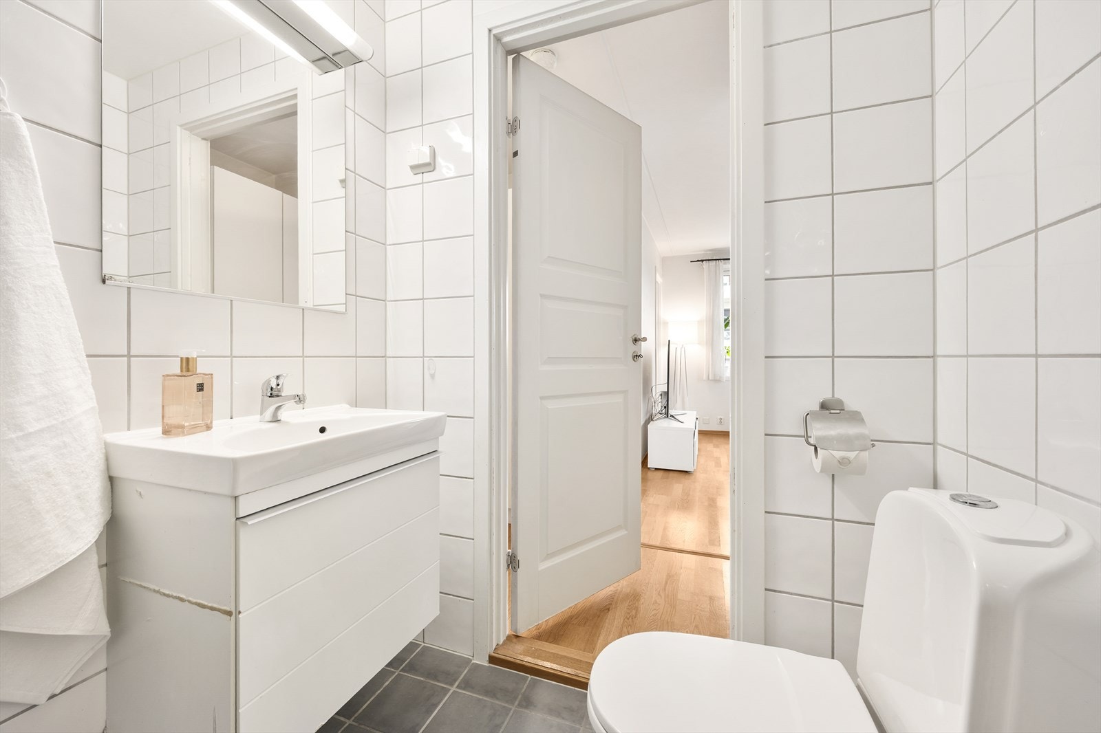 Badet er innredet med servant med underskap, speil og lys, dusjhjørne og toalett. Galleribilde