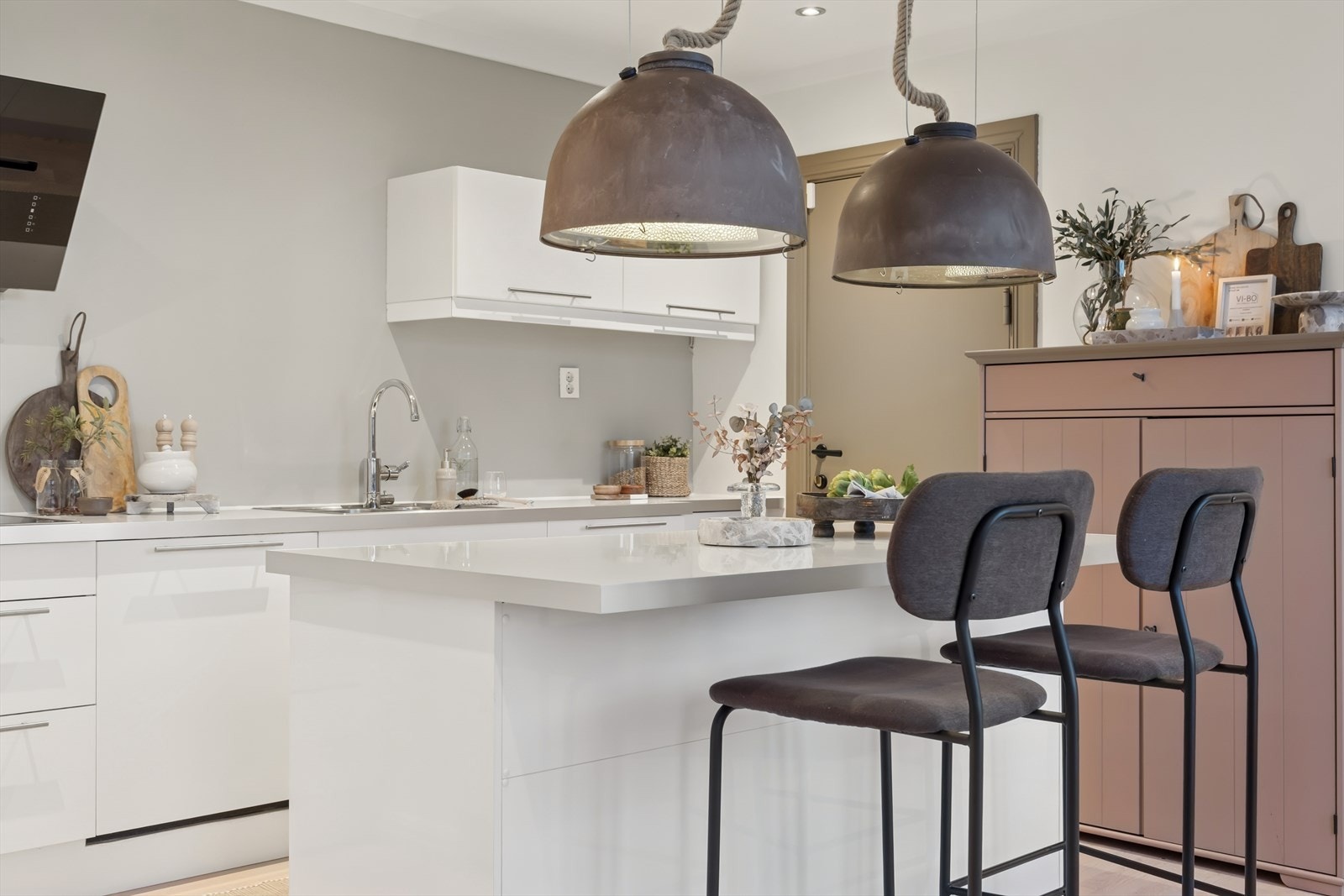 Lyst og moderne kjøkken med åpen løsning mot spisestue. Praktisk kjøkkenøy med barløsning, integrerte hvitevarer og stilrene detaljer som gir rommet et elegant preg. Galleribilde