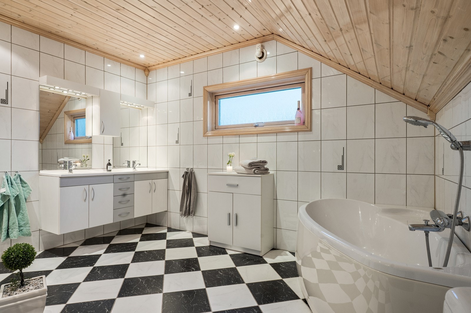 Flislagte vegger og gulv gir badet et stilrent uttrykk, mens taket i tre tilfører varme. Galleribilde