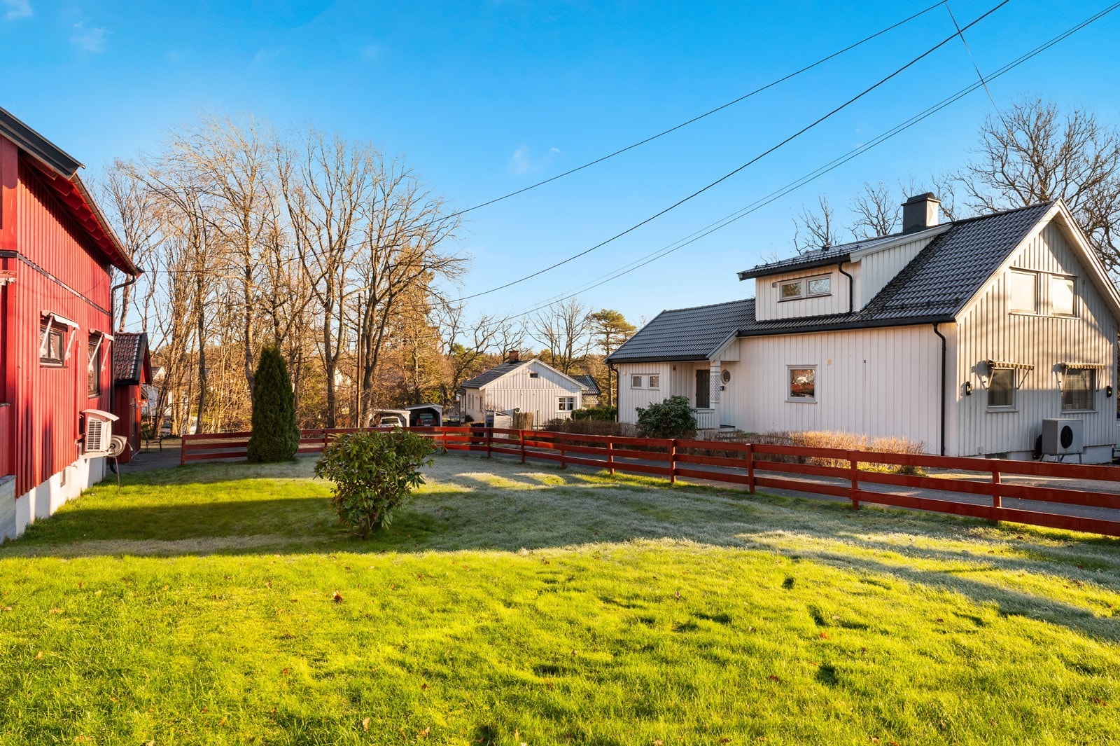 Tomten har enkel adkomst med bilparkering rett ved inngangspartiet, omgitt av frodig plen og gjerder. Galleribilde