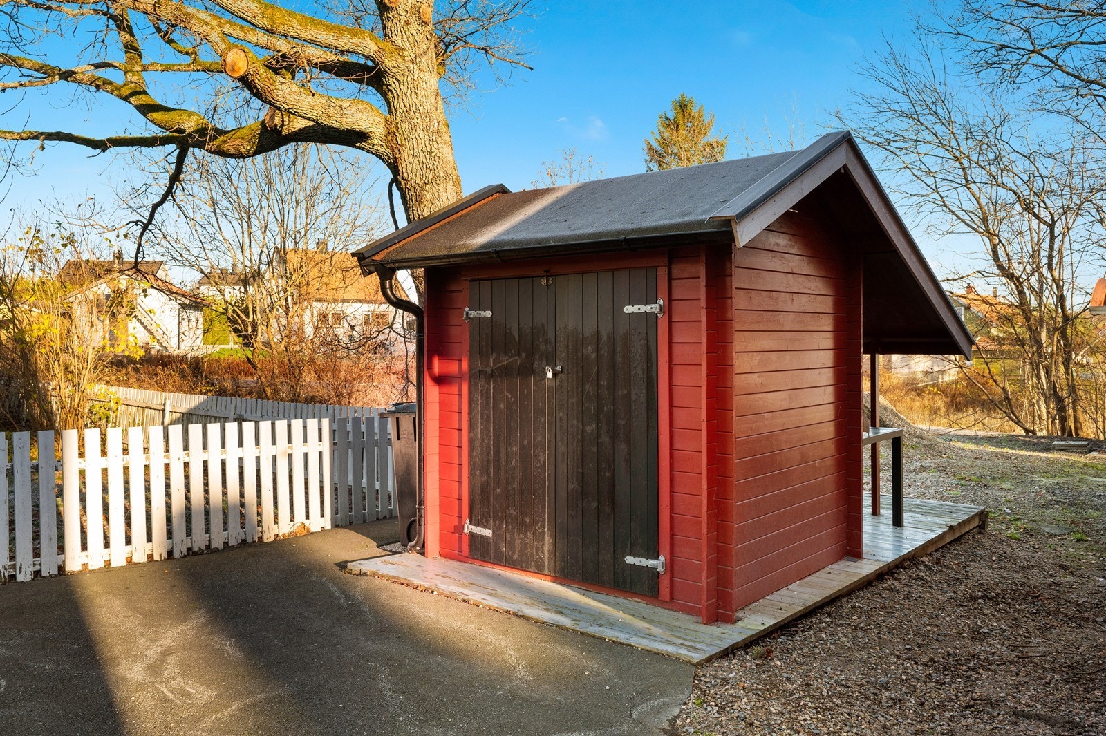 Rødmalt bod med skråtak gir praktisk oppbevaringsplass i gården. Galleribilde