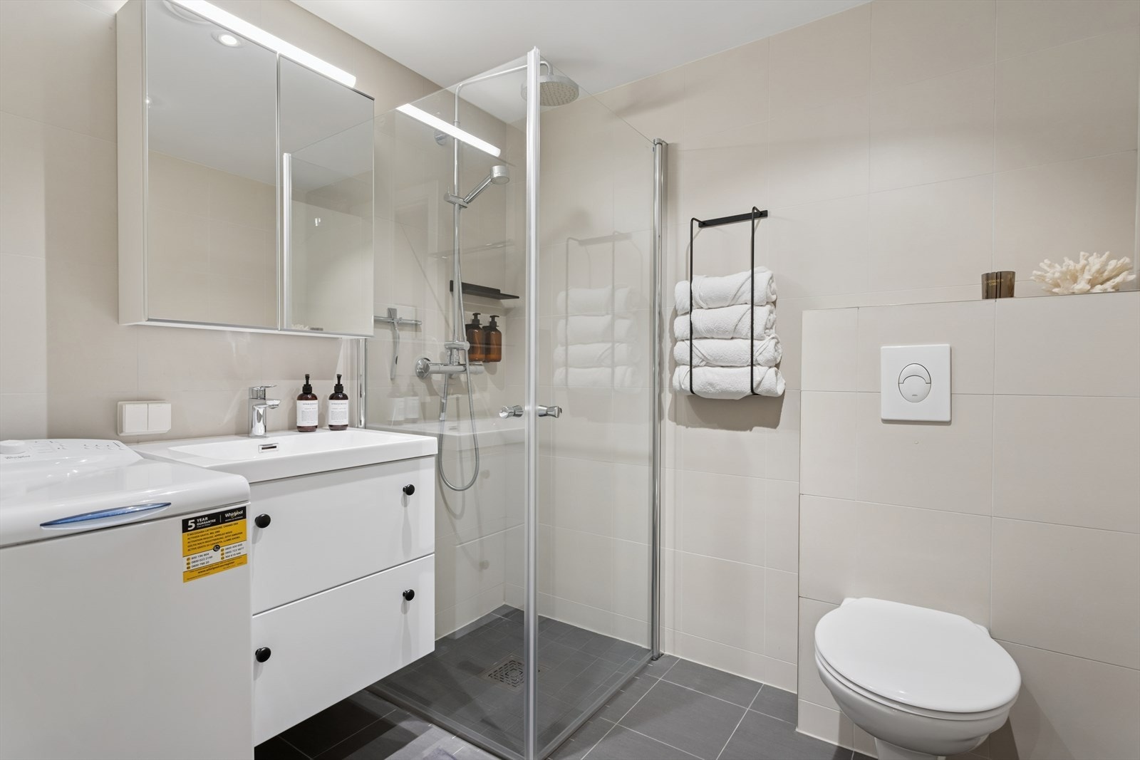 Badet er praktisk innredet med vegghengt toalett, servant med underskap, samt overskap med speilfronter og overlys som gir gode oppbevaringsmuligheter. Galleribilde