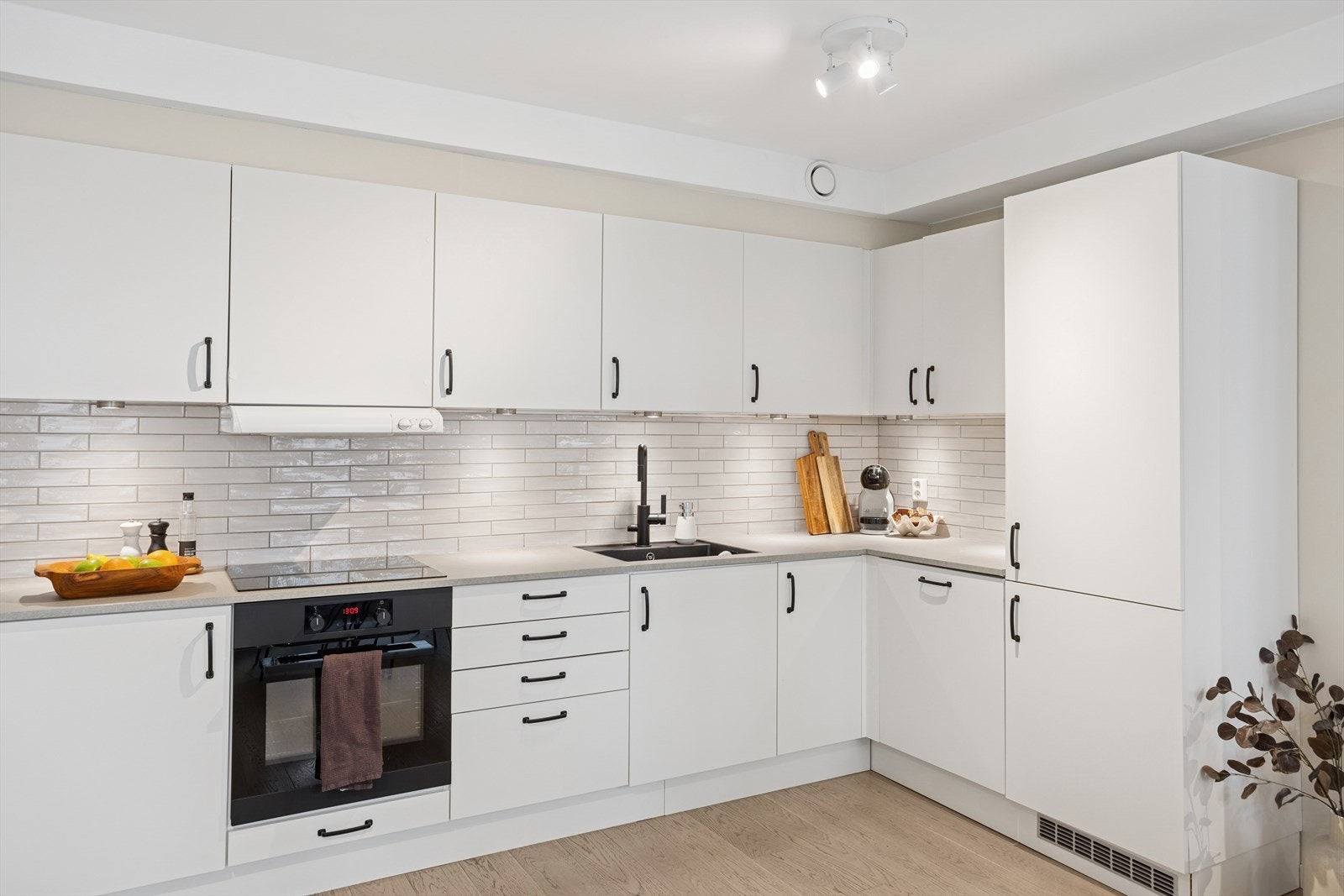 I 2023 fikk kjøkkenet flere oppgraderinger, inkludert ny benkeplate, armatur og vask. Kjøkkenet har slette laminerte fronter, en laminat benkeplate med fliser over, og en enkel underlimt kompositt oppvaskkum. Galleribilde