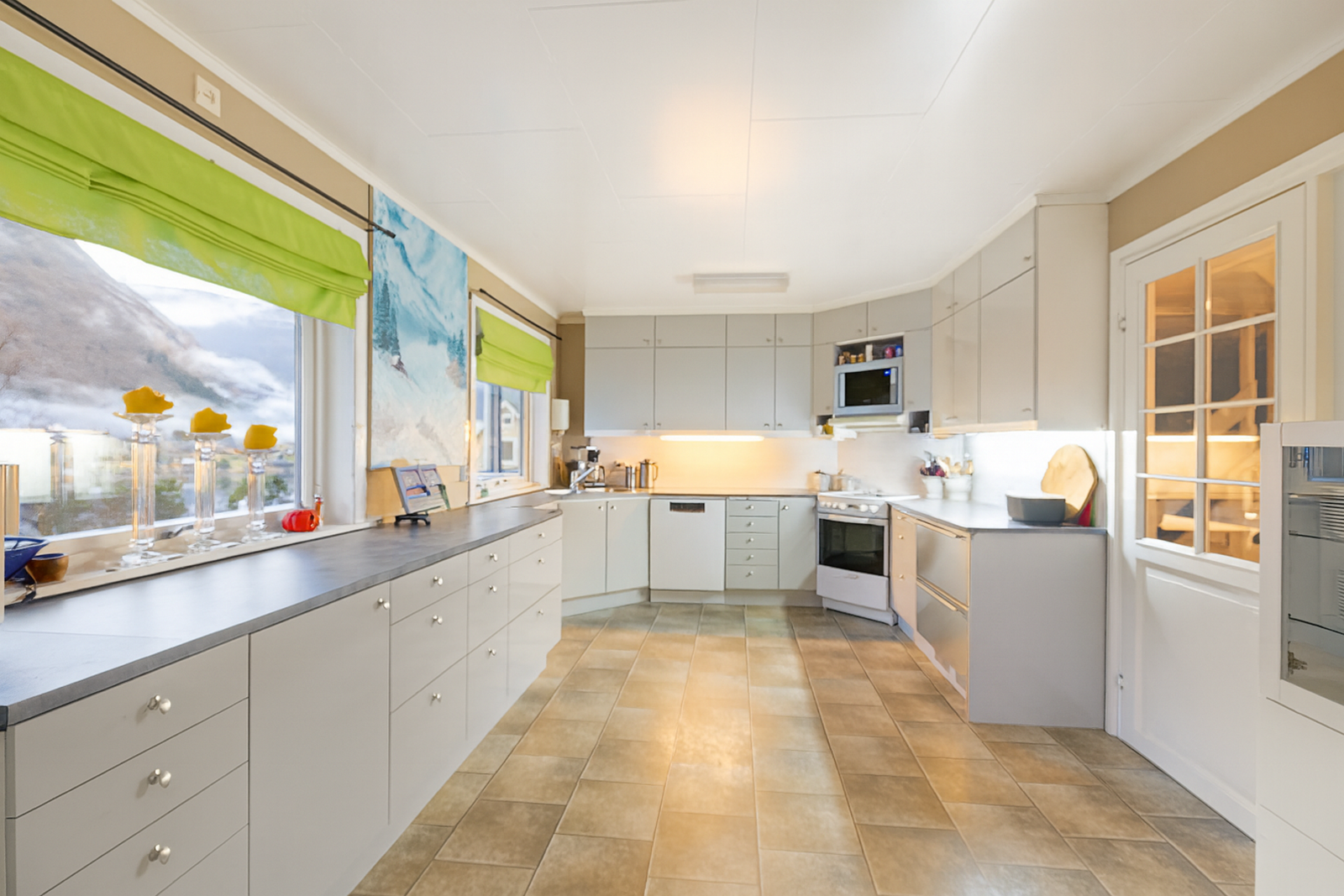 Kjøkkenet har takhøy innredning med malte, slette fronter. Galleribilde