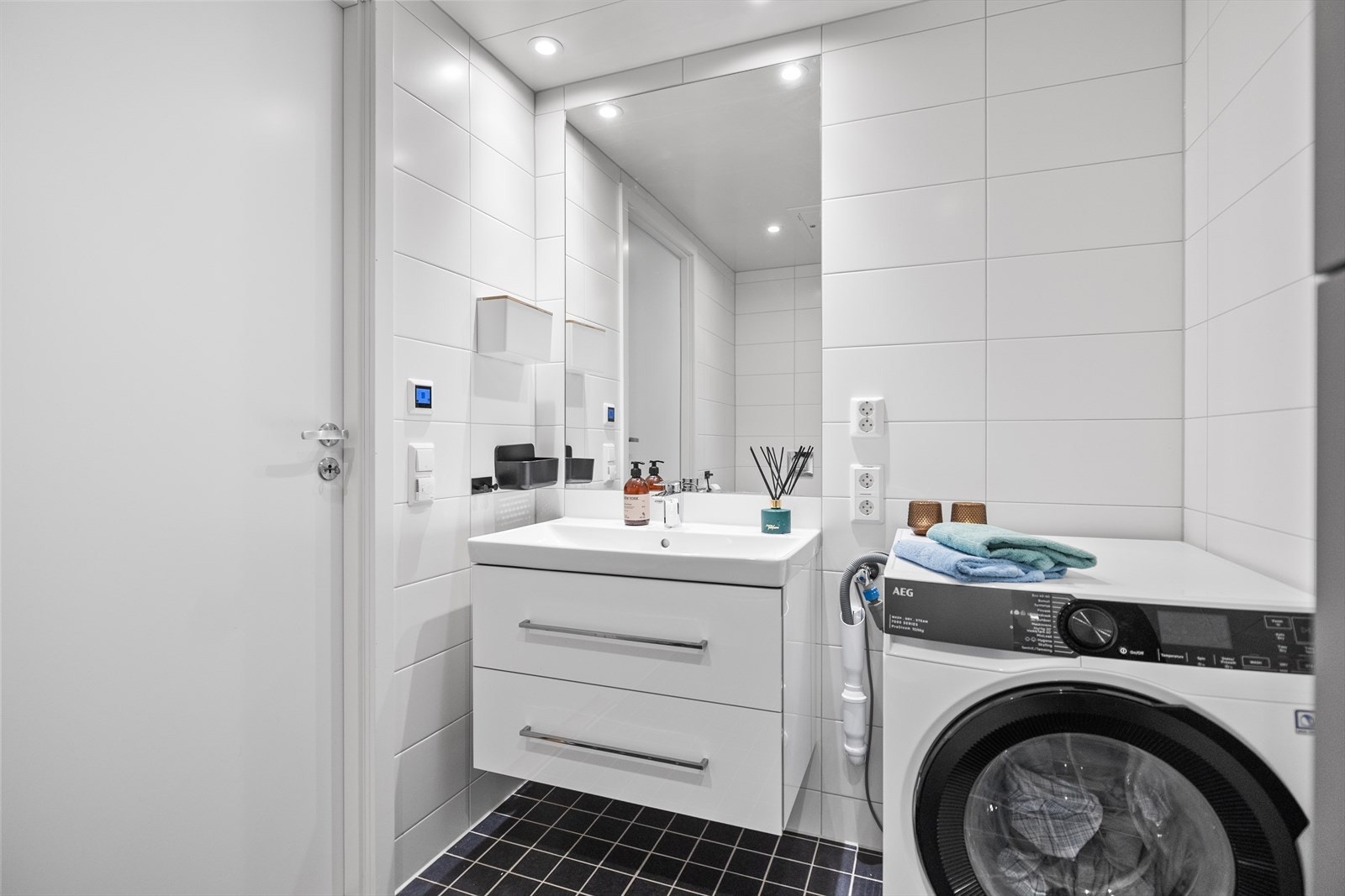 Badet nede har vegghengt toalett, dusjhjørne, servant med skuffer og opplegg for vaskemaskin. Galleribilde