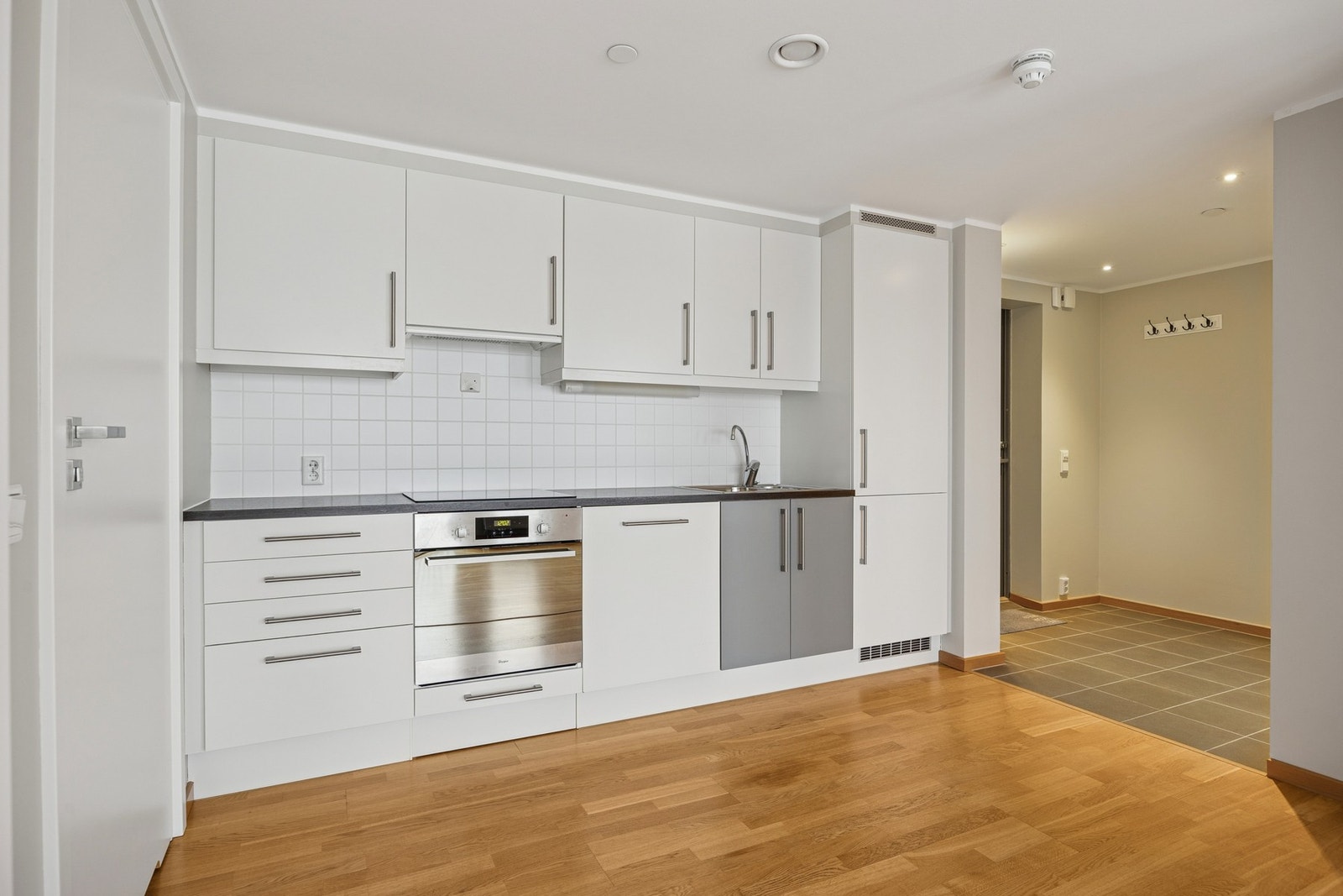 Boligen har en åpen og sosial kjøkkenløsning med innredning fra byggeår, bestående av glatte fronter og laminert benkeplate. Galleribilde