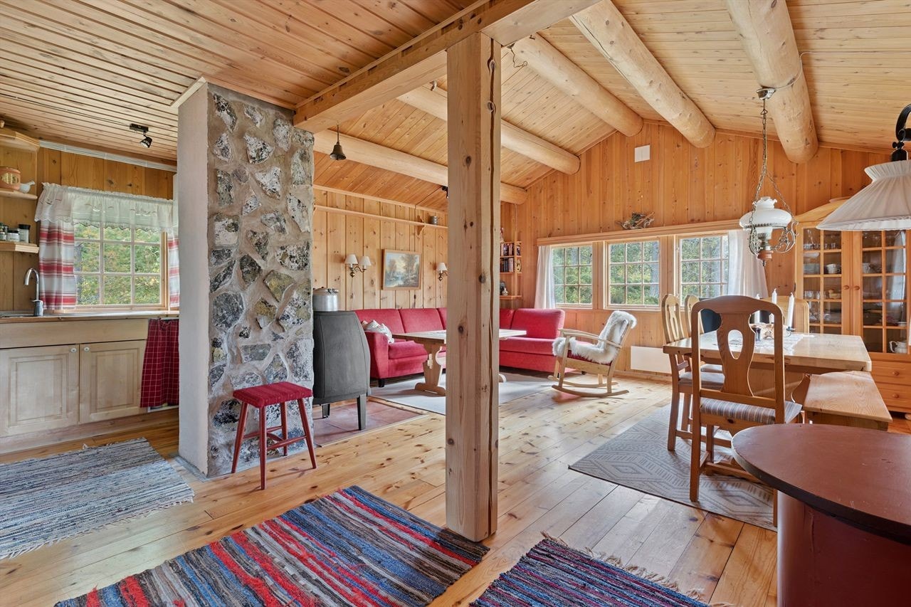 Stuen og kjøkkenet utgjør et lunt og sosialt allrom, sentrert rundt den natursteinsforblendede pipen. Galleribilde