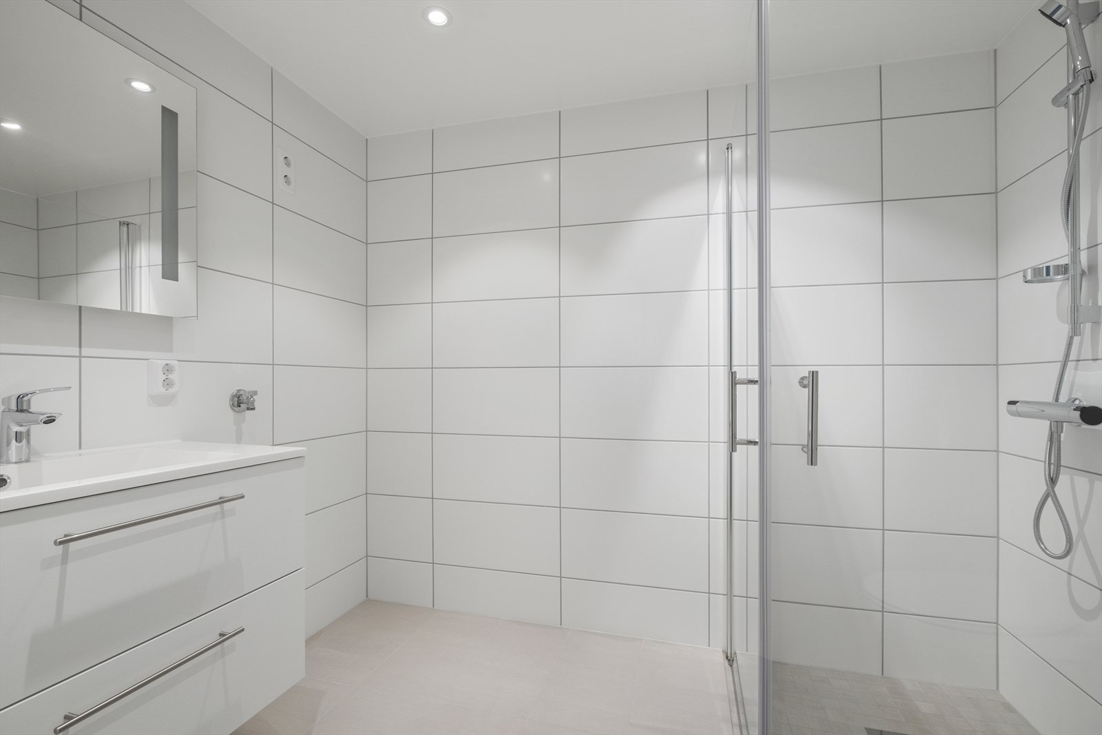 Flott flislagt baderom på 4,3m². Rommet er innredet med dusjhjørne, speil med belysning, vegghengt wc, og servant med underskap. Elektriske kabler varmer opp rommet. Galleribilde