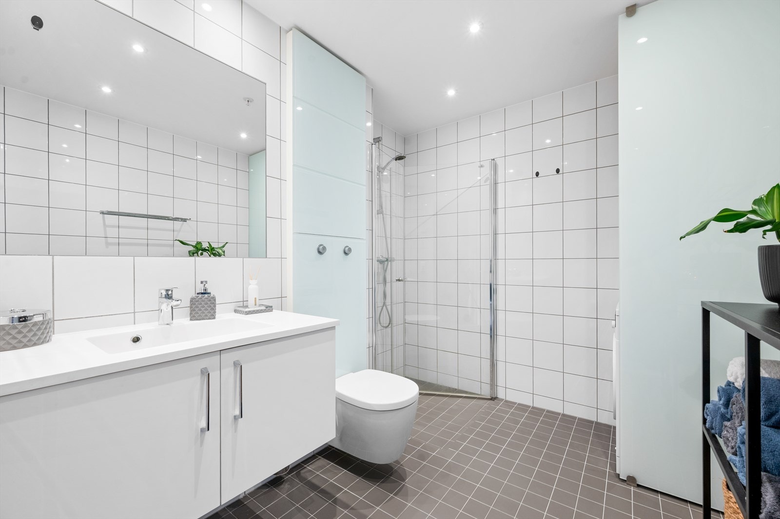 Lyst og pent bad med toalett, dusjhjørne og servant med skap. Galleribilde