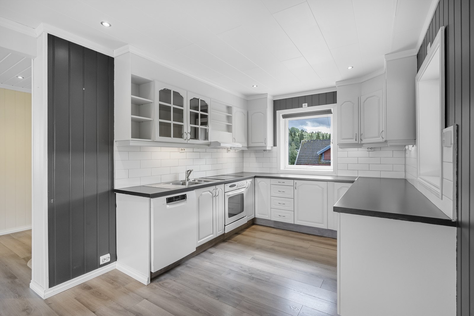 Kjøkkenet har lys, innholdsrik innredning i malte folierte plater med over- og underskap, laminat benkeplate i trefylling og oppvaskkum med kran av stål. Galleribilde