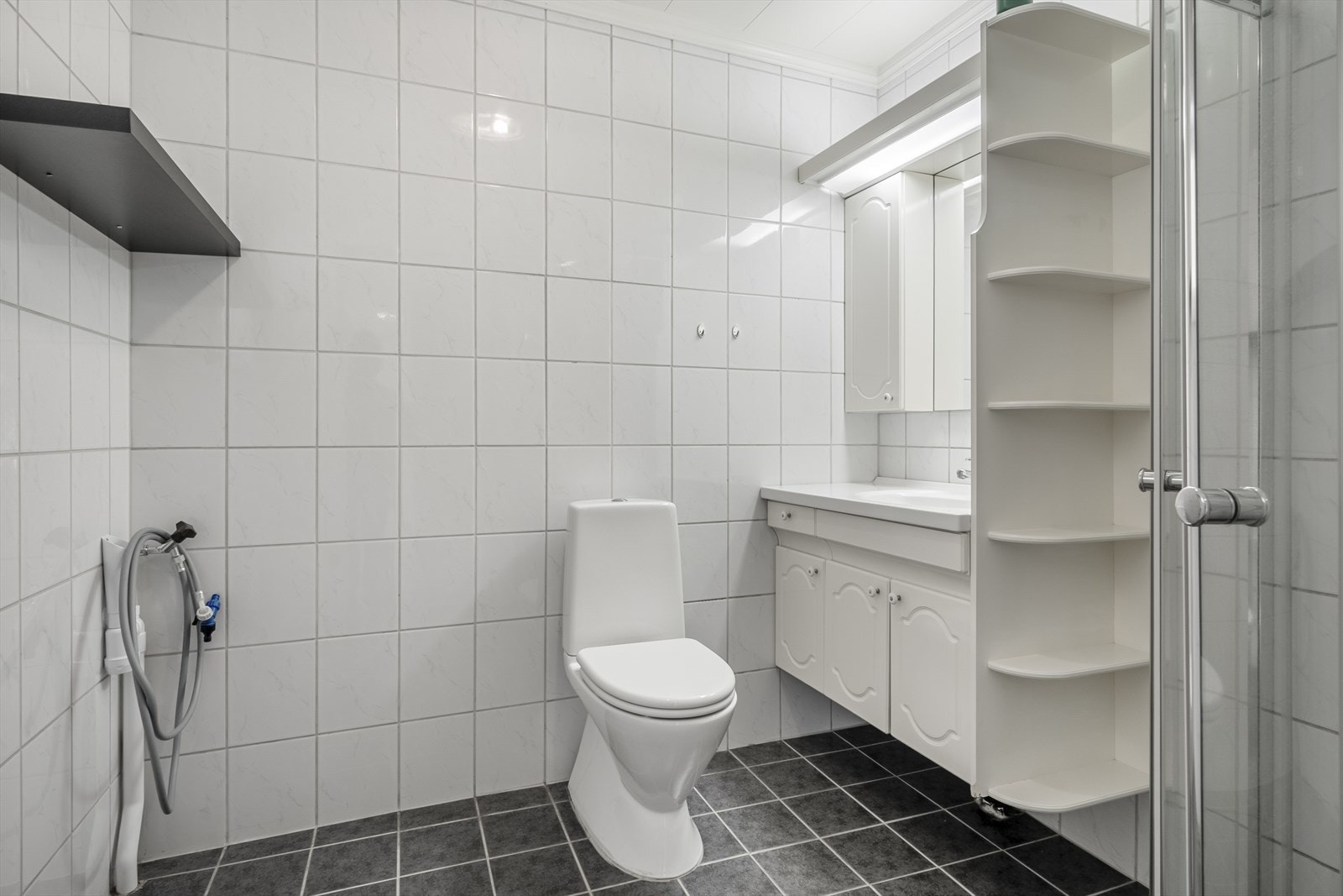 På badet er det flislagte vegger og flislagt gulv med varmekabler. Lys baderomsinnredning, dusj på vegg og toalett. På badet er det også opplegg for vaskemaskin og elektrisk styrt vifte. Galleribilde