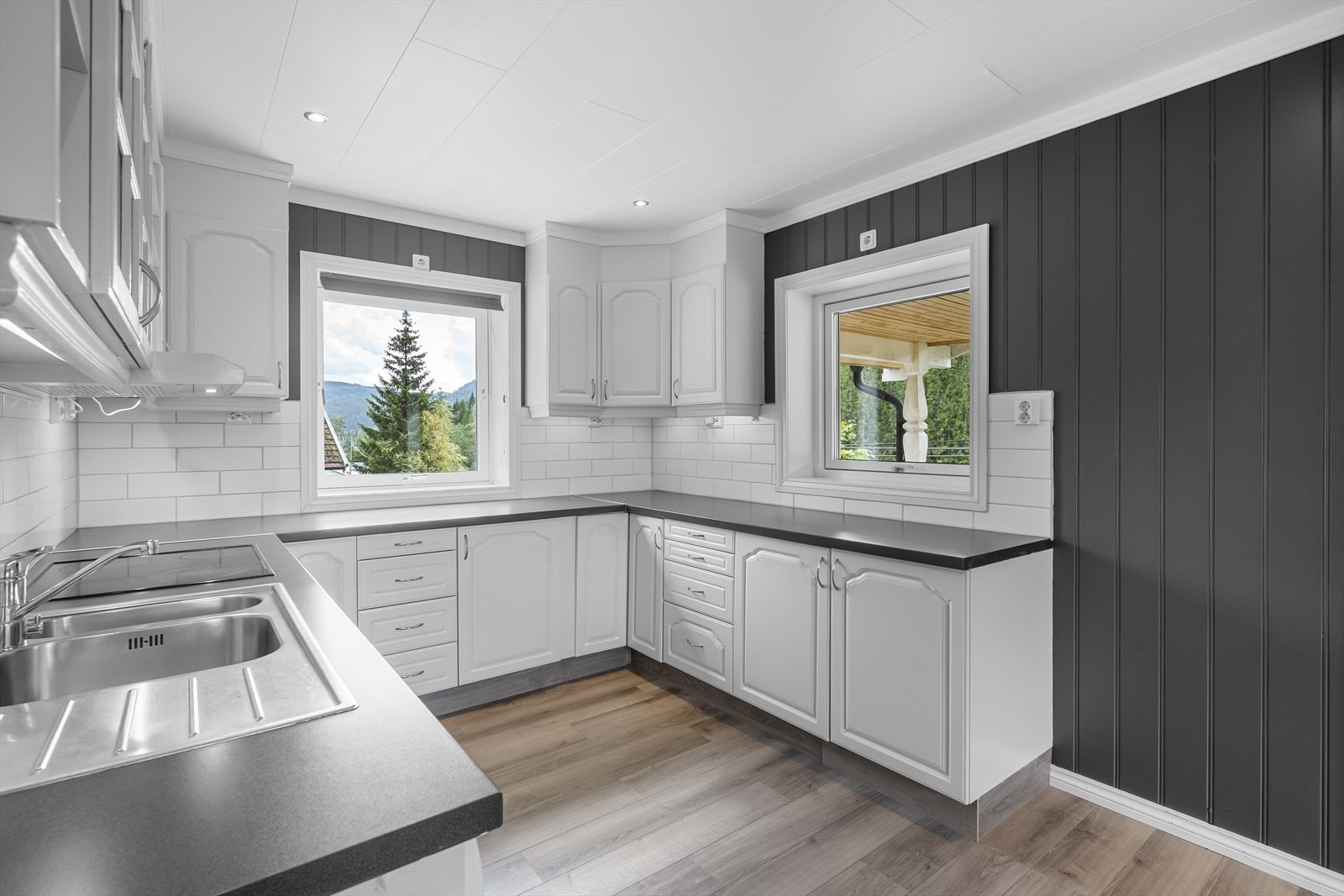 Mellom benk og overskap er det praktiske fliser på vegg. Integrerte hvitevarer med komfyr og koketopp. Opplegg for oppvaskmaskin. Kjøkkenventilator med avtrekk ut. Galleribilde