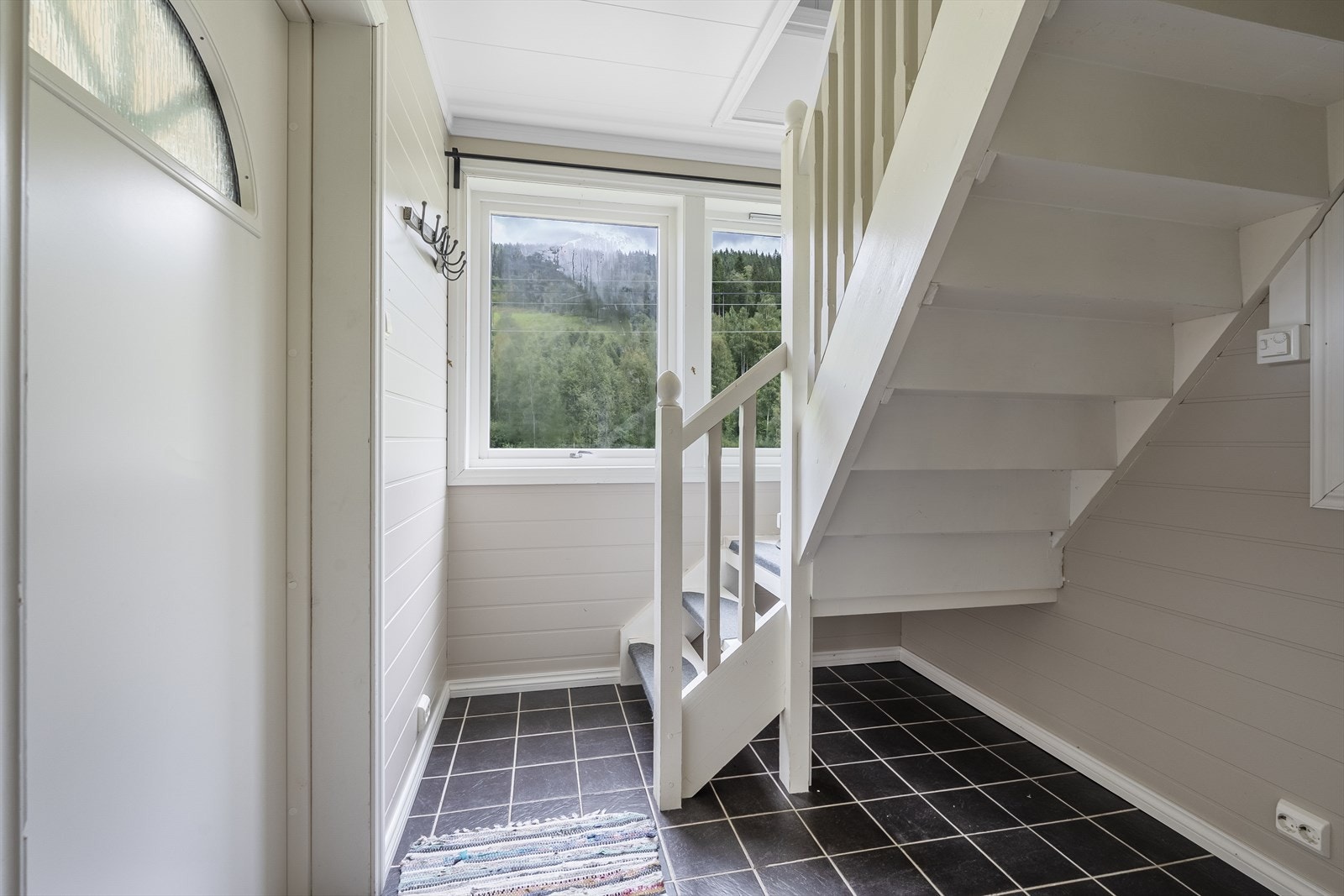 I vindfanget er det flislagt gulv med varmekabler og godt med oppbevaringsplass under trappen opp til 2. etasje. Galleribilde