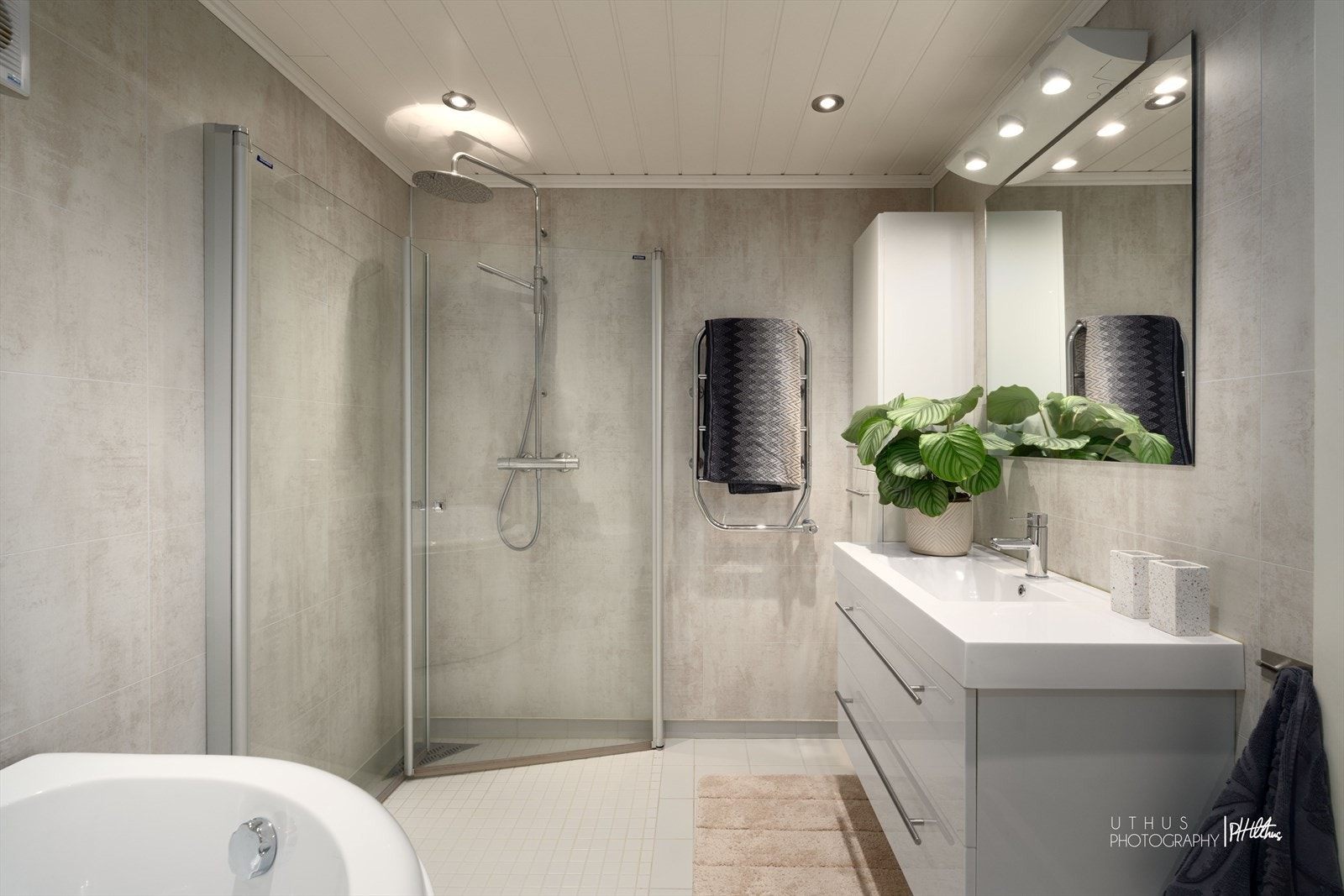 Pent baderom med flislagt gulv med varmekabler og vegger med baderomsplater. Galleribilde