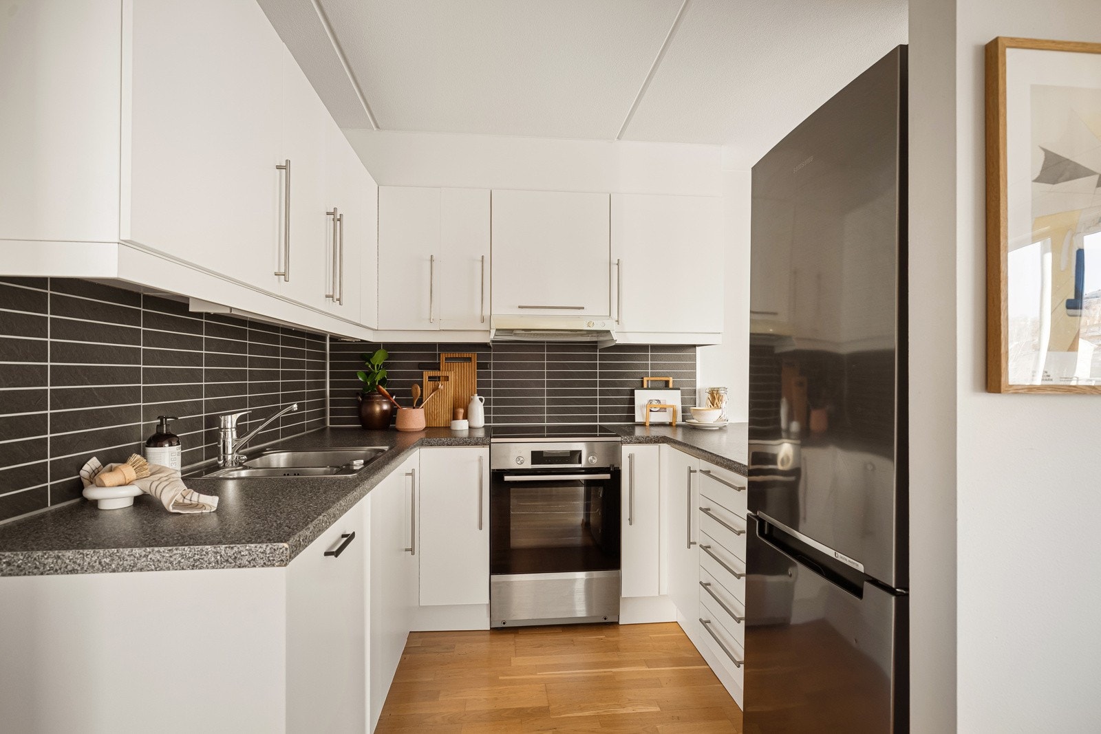 Stilig og funksjonelt kjøkken med glatte, hvite fronter og laminert benkeplate. Det er også rikelig med plass i over- og underskap. Galleribilde