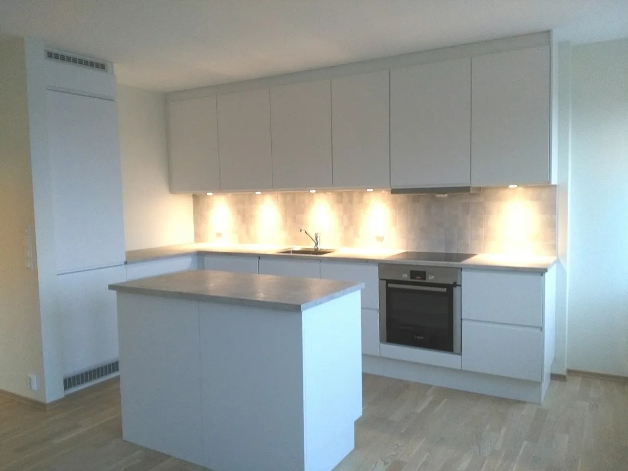 Pent kjøkken i hvite fronter med med alt av hvitevarer integrert. Galleribilde