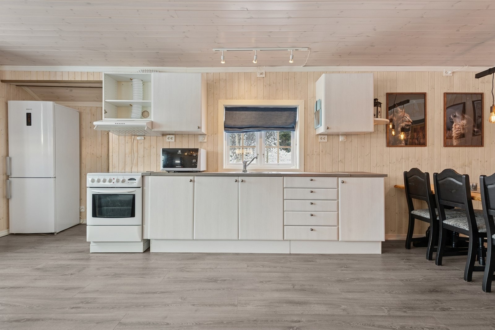 Kjøkkeninnredningen har hvite, glatte fronter og laminat benkeplate. Galleribilde