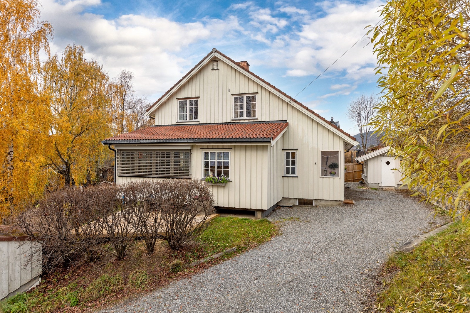 Velholdt enebolig med klassisk uttrykk, innrammet av vakker natur og lune høstfarger. Innkjørsel med god plass til parkering og adkomst til garasje på eiendommen. Galleribilde