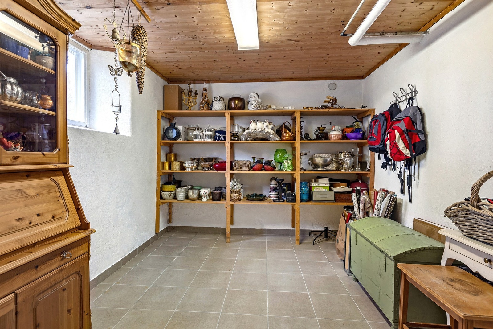 Lyst og praktisk bodrom med flislagt gulv, trehyller og god plass til oppbevaring av utstyr og sesongartikler. Galleribilde