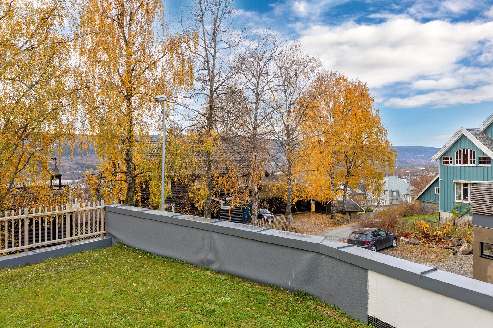Utsyn over nærområdet - omgitt av trær som gir både skjerming og et lunt, grønt preg. Naboeiendommen har garasje under dette arealet og eier således også dette arealet. . Galleribilde