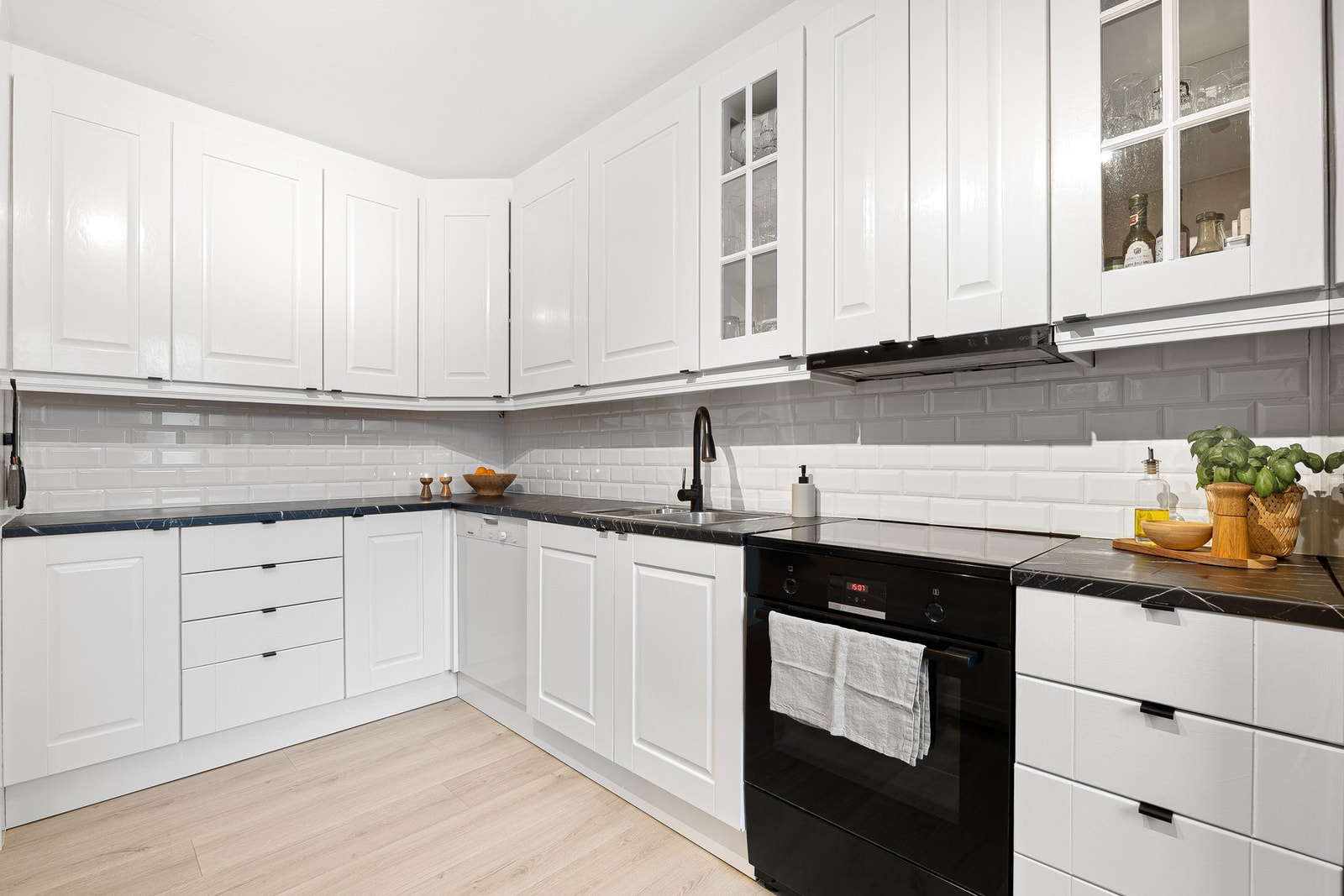 Her har du rikelig med skap, skuffe og benkeplass. Mellom over- og underskap er det tidløse fliser som står i fin stil til de øvrige fargetonene på kjøkkenet. Galleribilde