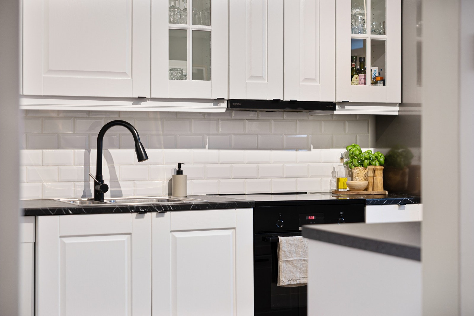 Separat kjøkken måler 9,9 kvm med tidløs innredning i hvitt og kontrastfulle sorte benkeplater. Galleribilde