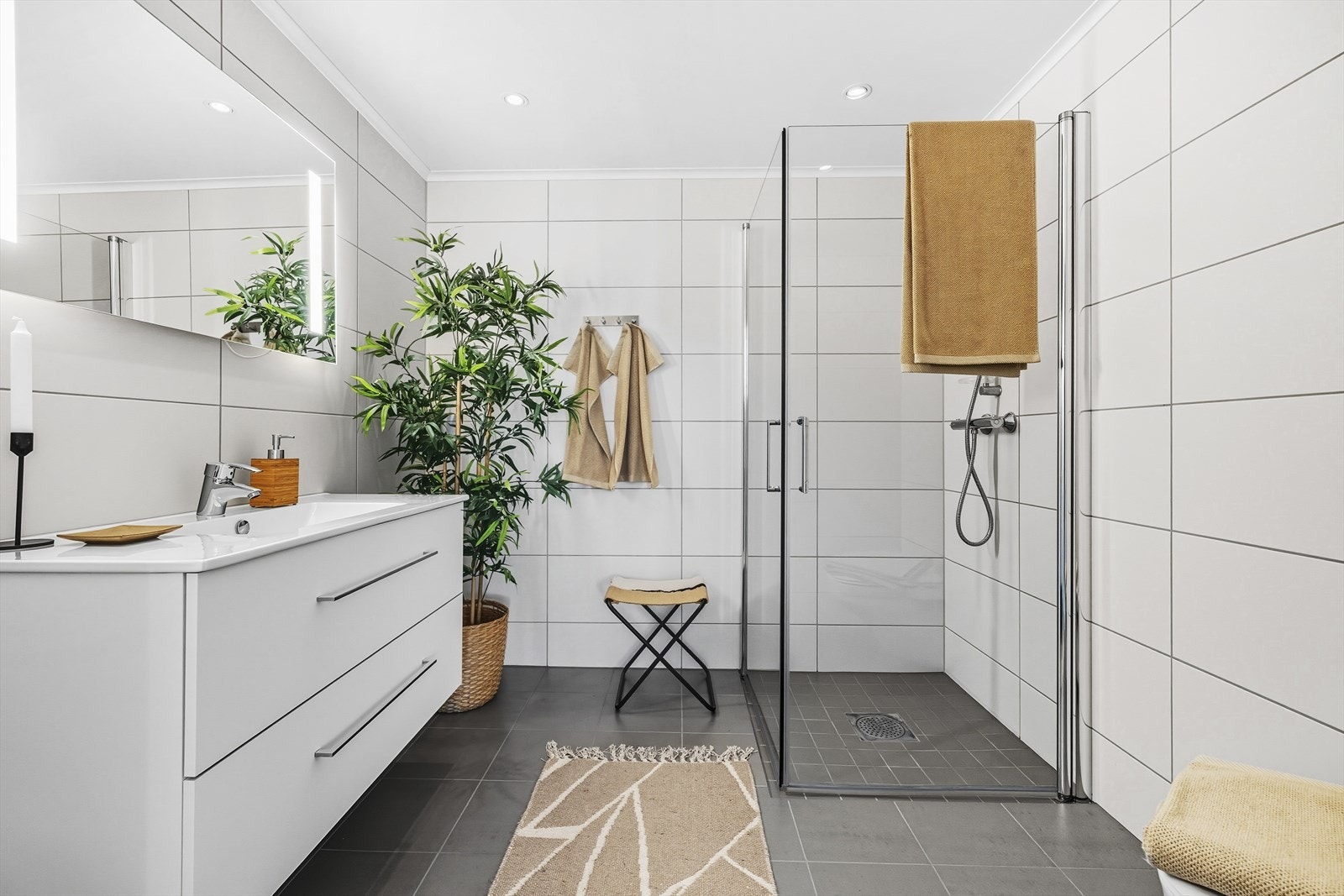 Baderommet har nøytrale fliser på vegger og gulv, med varmekabler Galleribilde