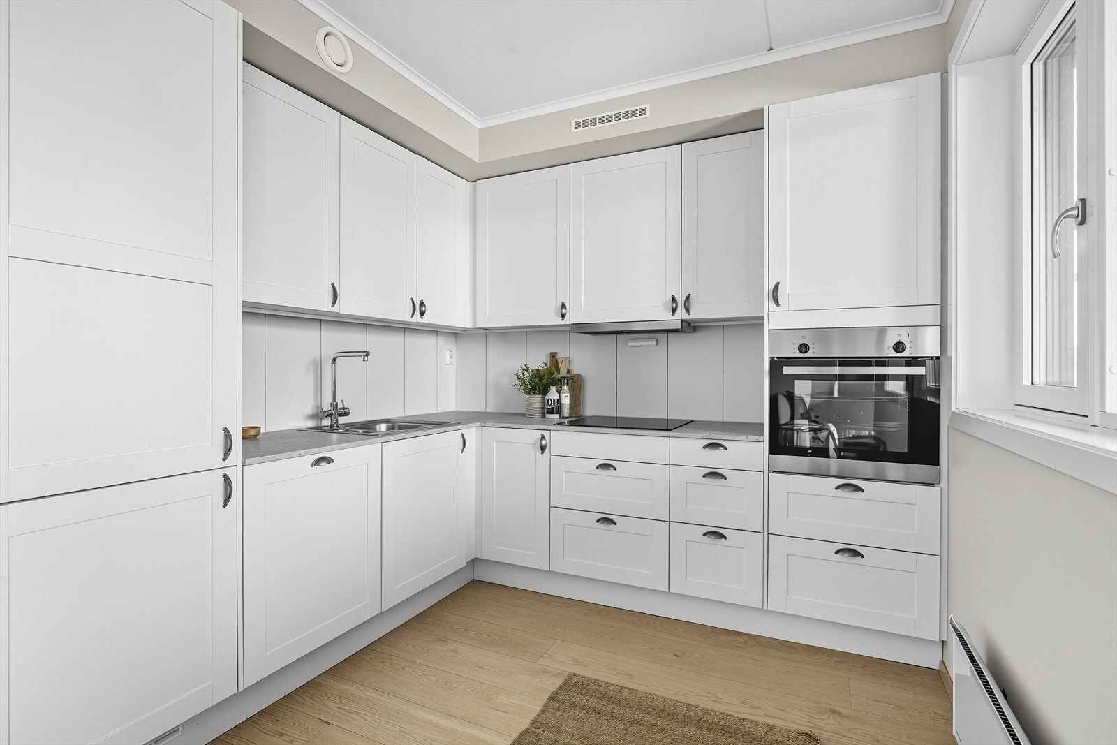 Pen kjøkkeninnredning med hvite lett profilerte fronter på over- og underskap, fra Sigdal Scala Galleribilde