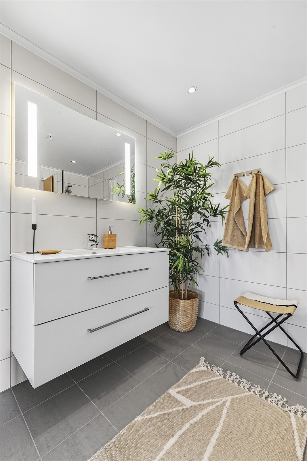 Moderne baderomsinnredning med skuffer og overliggende heldekkende servant, tilhørende speil med belysning Galleribilde