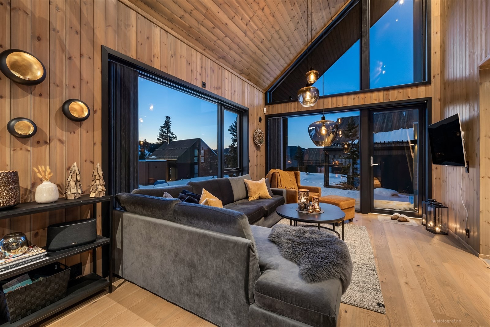 Stor og innbydende stue med en stavs eikeparkett på gulv og trepanel på vegg. Galleribilde