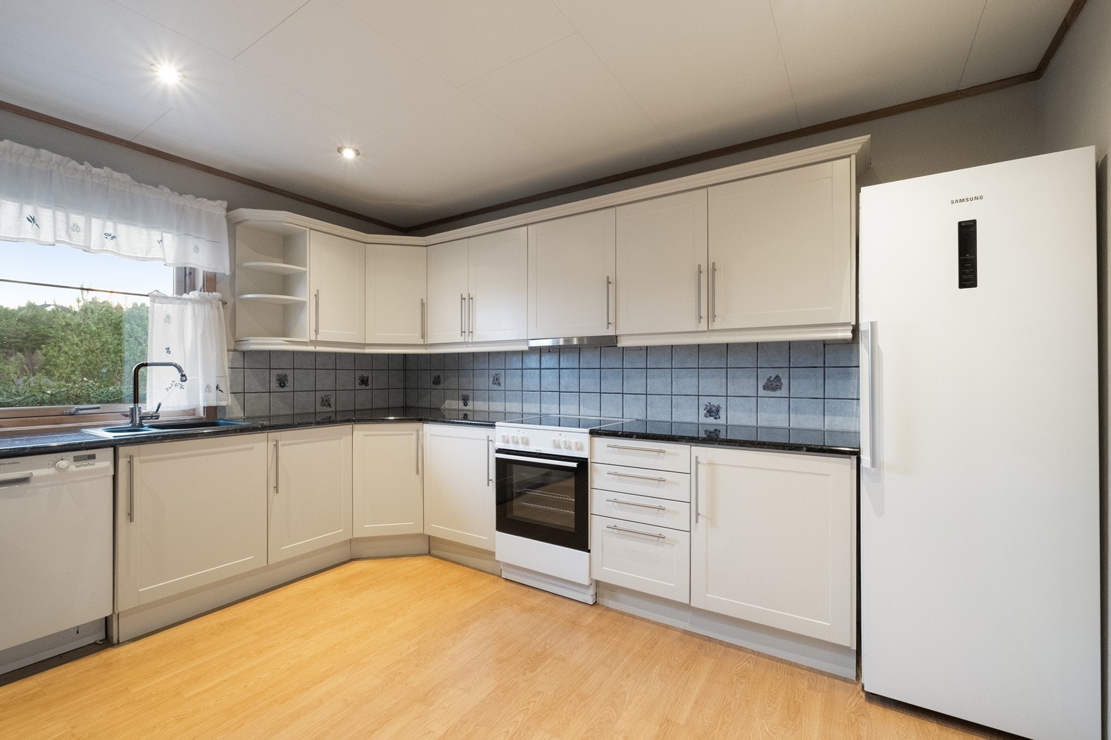 Kjøkkenet er rikt innredet med hvit, tidløs kjøkkenninredning med mørk benkeplate. Opplegg til oppvaskmaskin. Galleribilde