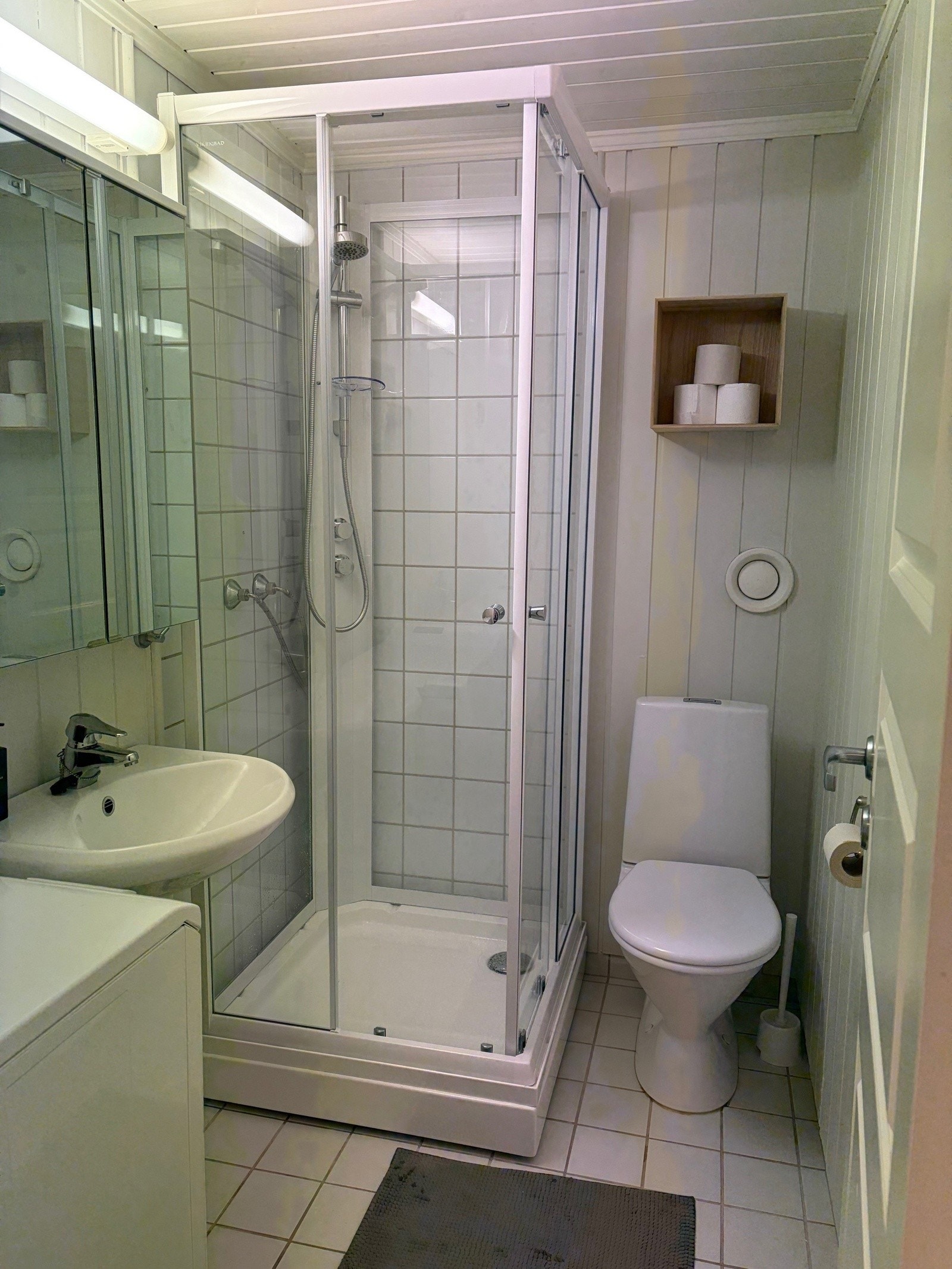 Badet har flislagt gulv og dusjkabinett Galleribilde