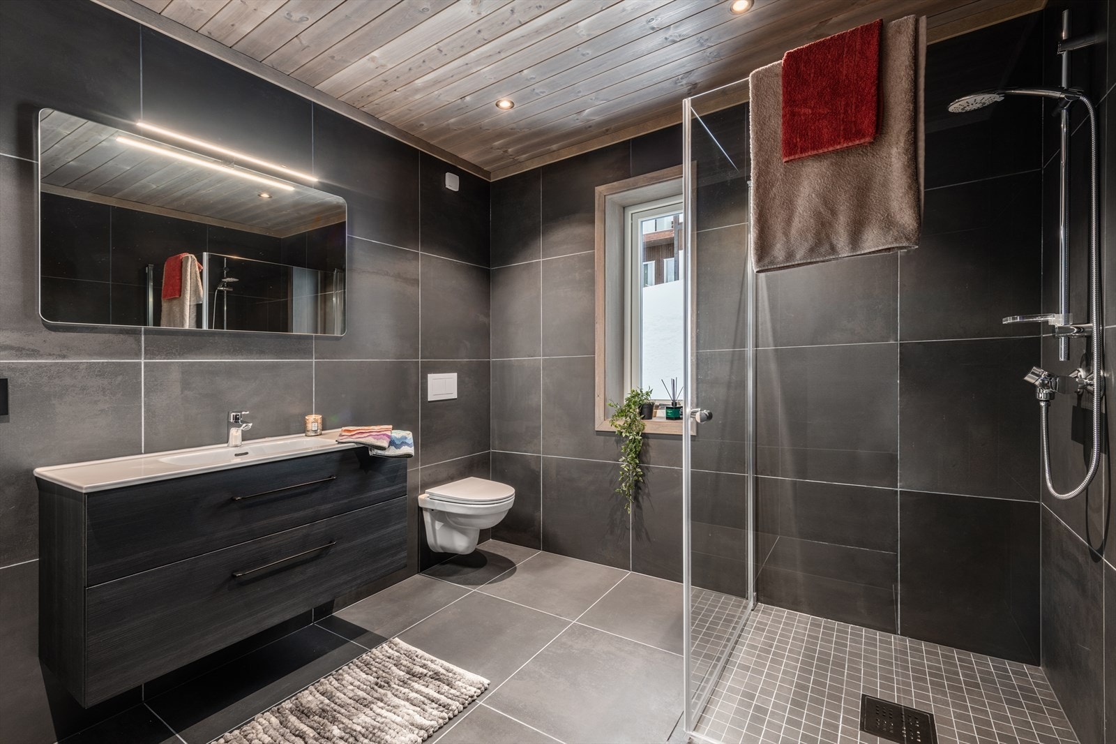 Badet er innredet med heldekkende servant med skuffer, vegghengt toalett og dusjhjørne. Galleribilde