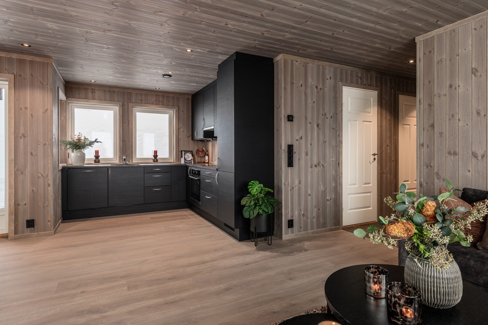 Stuen og kjøkkenet utgjør et sosialt oppholdsrom med farger som skaper en lun atmosfære. Galleribilde