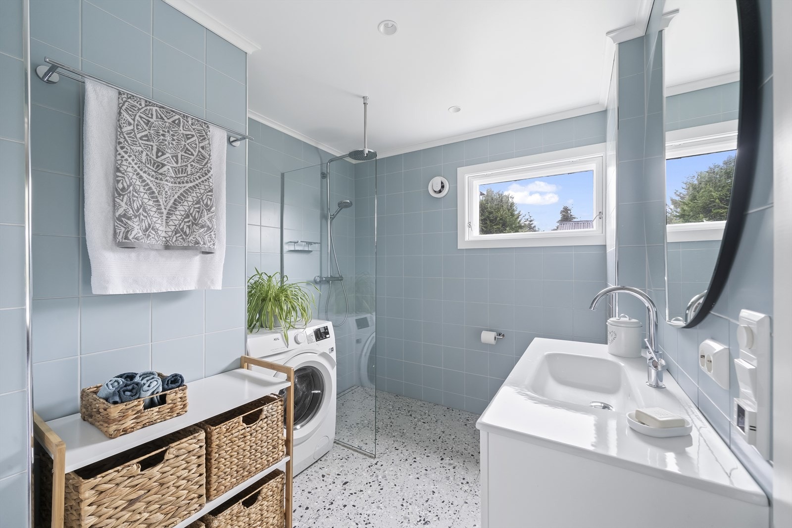 Lyst og moderne bad med dusjhjørne, baderomsinnredning og toalett. Opplegg til vaskemaskin og plass til tørketrommel over. Varmekabler i gulv. Galleribilde