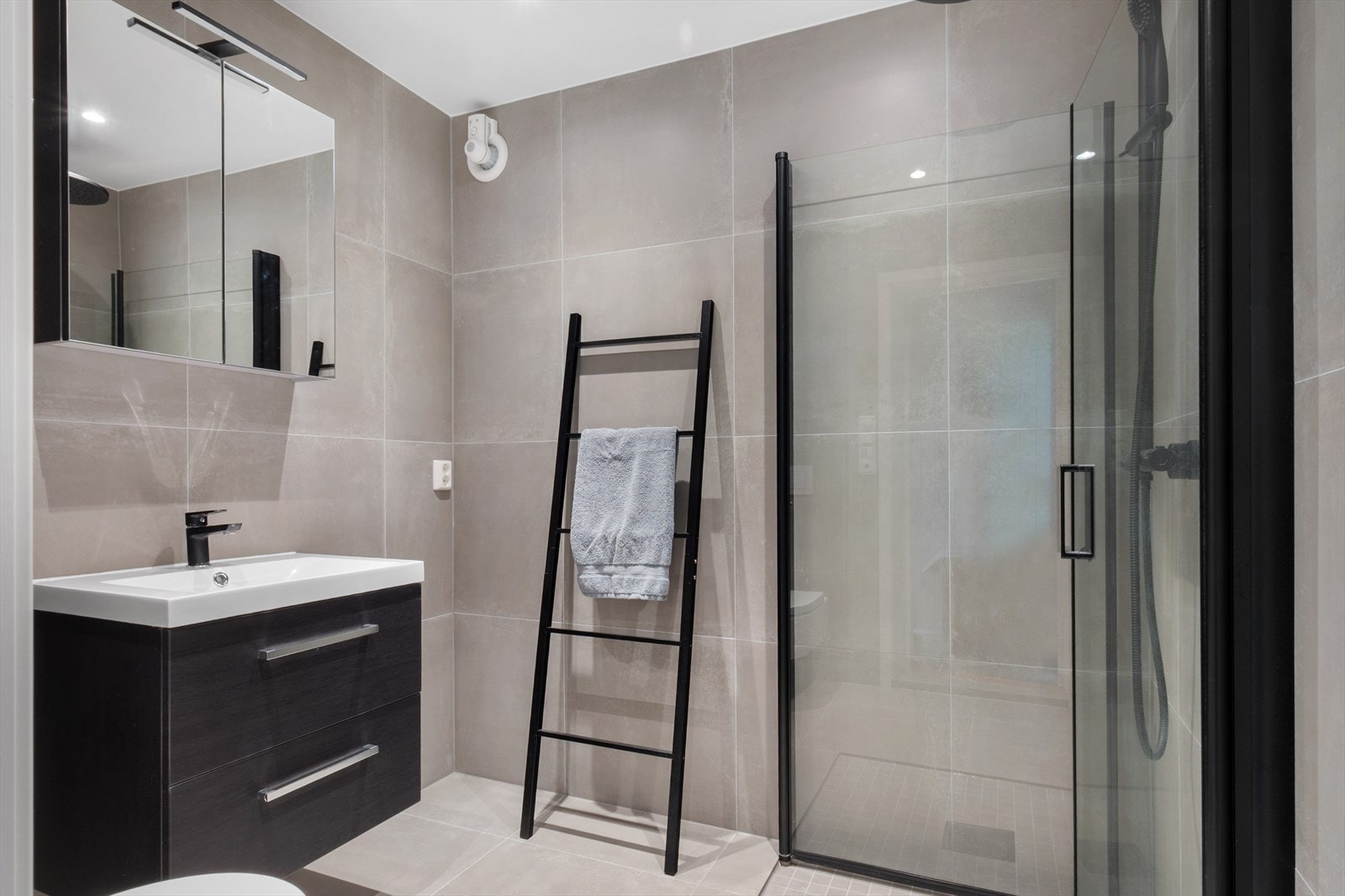 Badet ble renovert i 2024 og har flislagte overflater, gulvvarme, delikat innredning med sorte detaljer og opplegg for vaskemaskin. Galleribilde