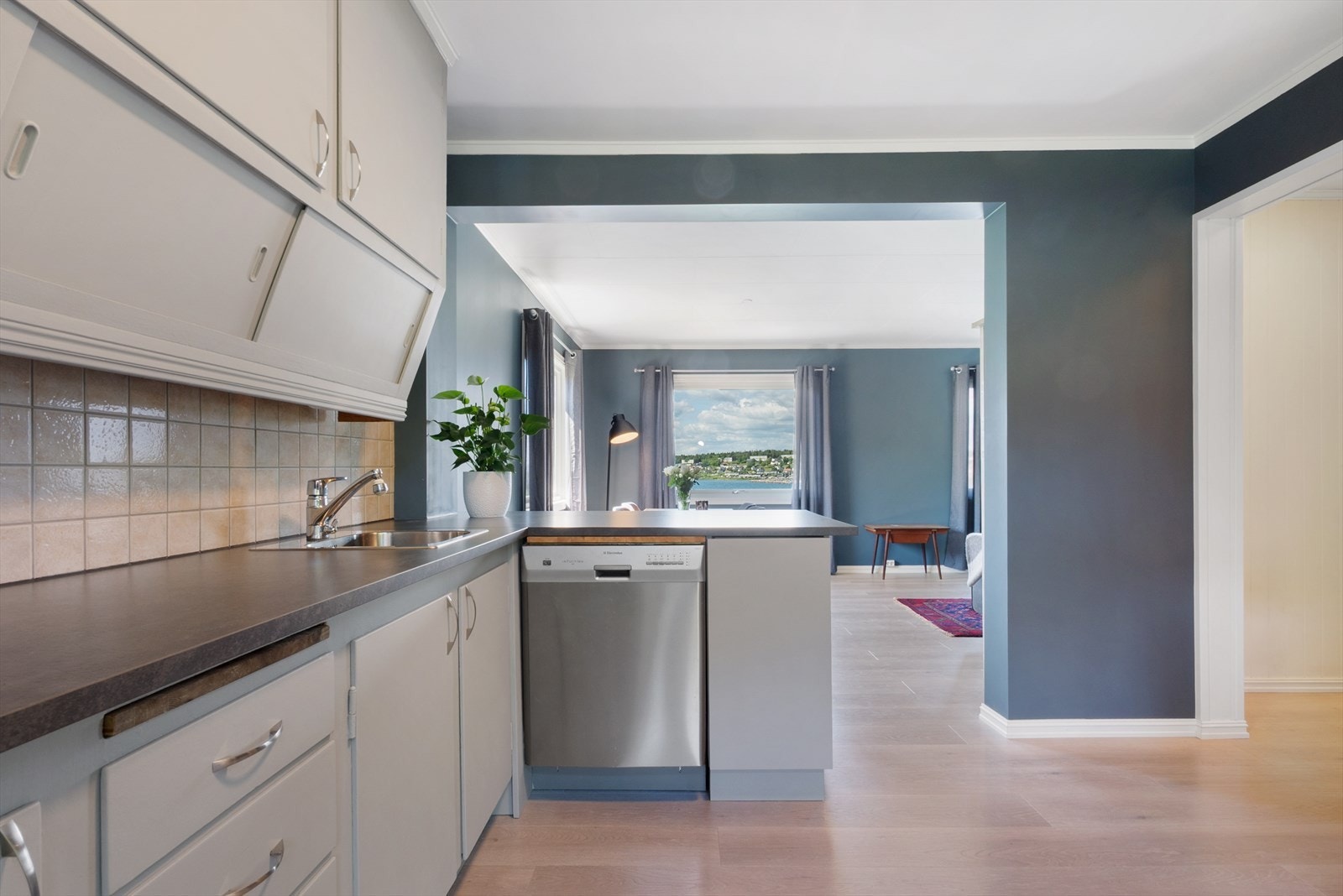 Kjøkken og stue ligger i delvis åpen løsning, adskilt av en kjøkkenhalvøy med oppbevaring, benkeplass og røropplegg for oppvaskmaskin. Galleribilde