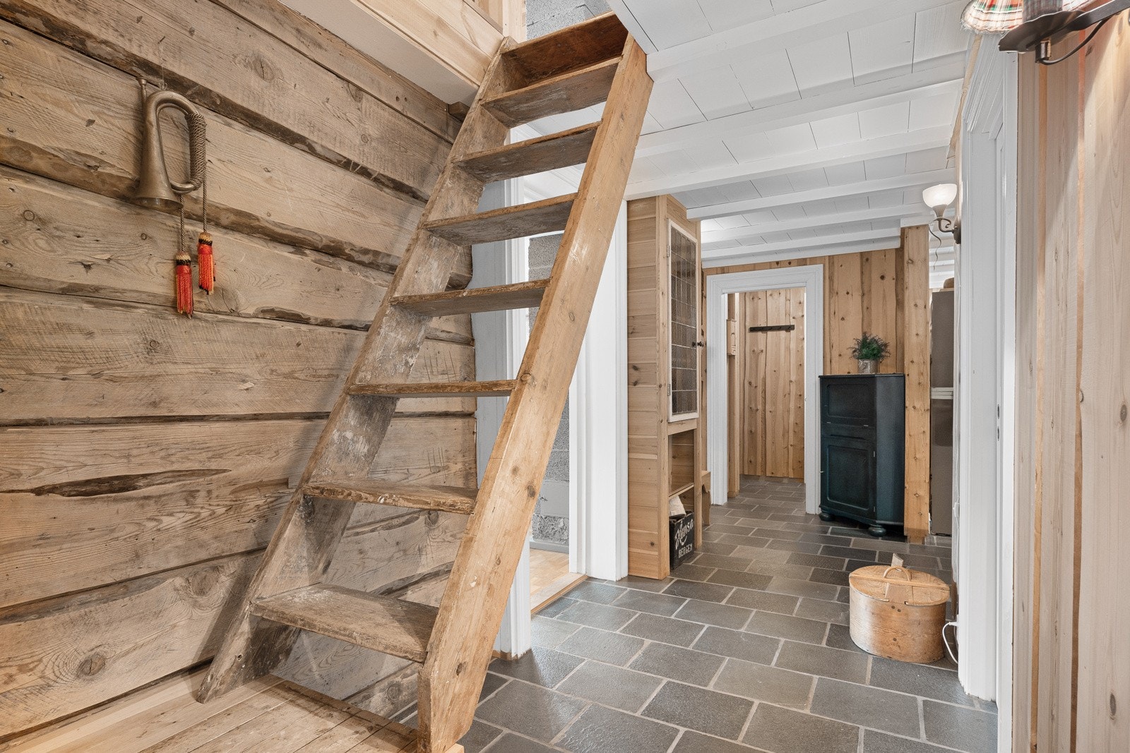 Vindfang og gang har skiferfliser på gulvet med varme, panel på vegger og hvitmalte tak. Galleribilde