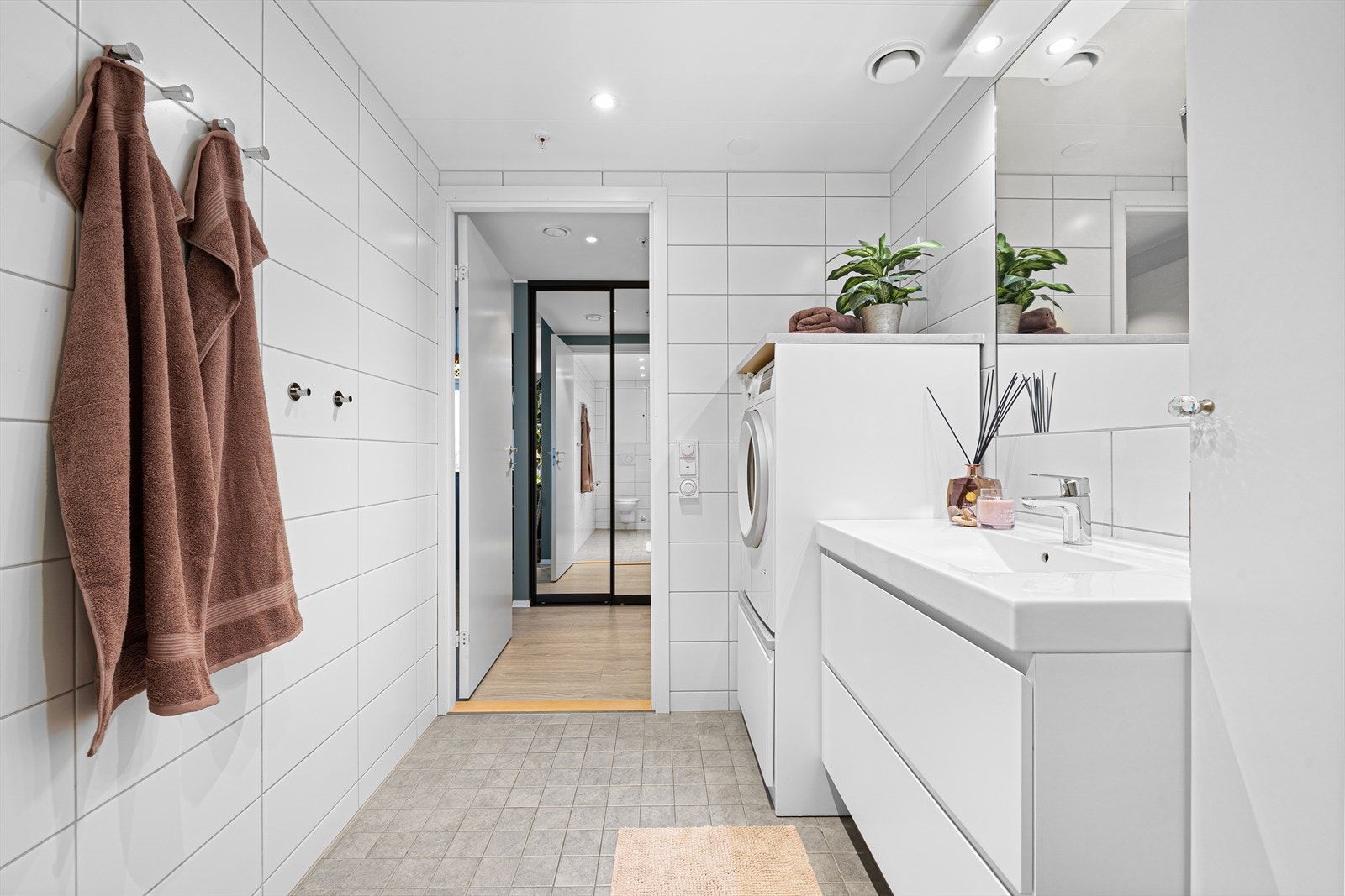 Pent flislagt bad med dusjkabinett, servantinnredning, toalett og opplegg for vaskemaskin. Galleribilde