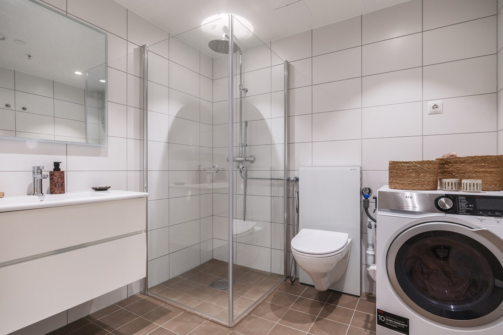 Fra gangen er det direkte adkomst til et delikat bad. Badet har mørke 20x20 fliser på gulv med varme og hvite 25x40 fliser på vegger. Badet er innredet med lys baderomsinnredning med speil med lys over, innfellbare dusjvegger og innebygd toalett. Galleribilde