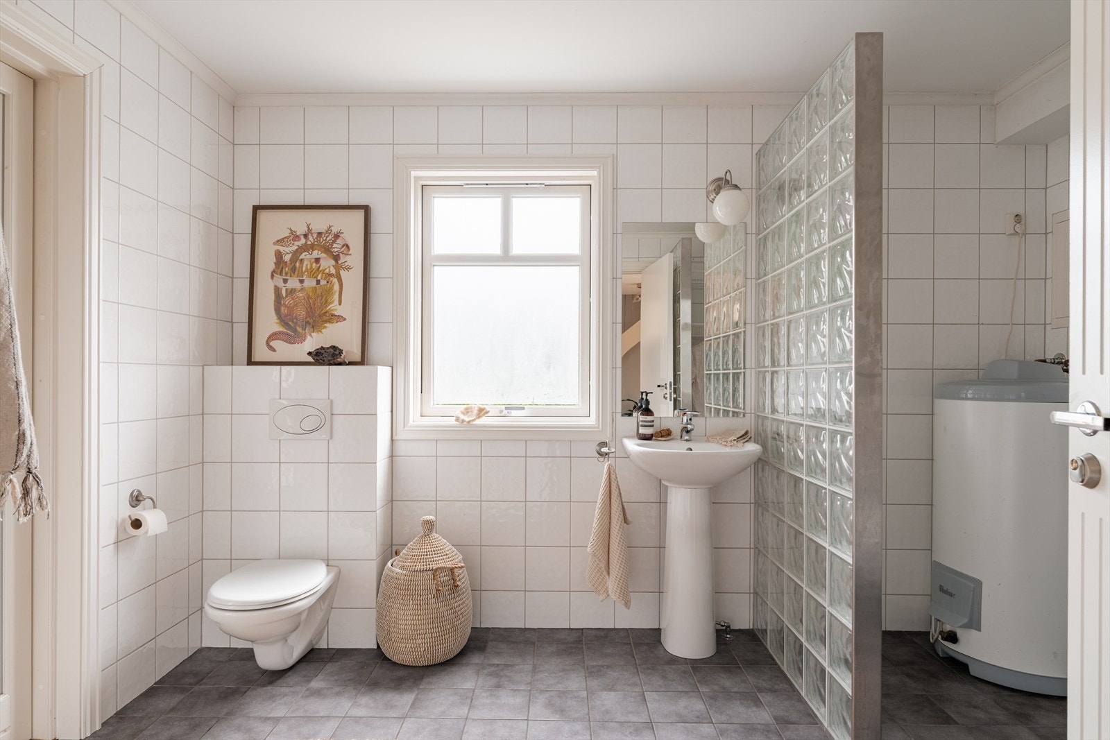 Badet er innredet med servant, speil med belysning, vegghengt toalett og dusj med skyvedører. Galleribilde