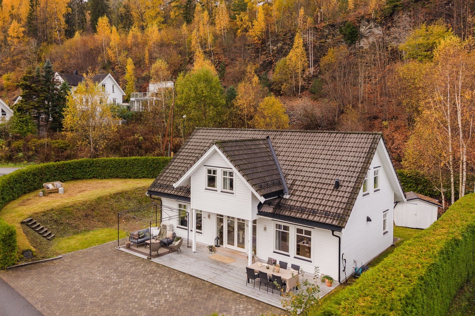 Eiendommen ligger på en pent opparbeidet tomt som omgis av hekk og skråning mot skog. Galleribilde