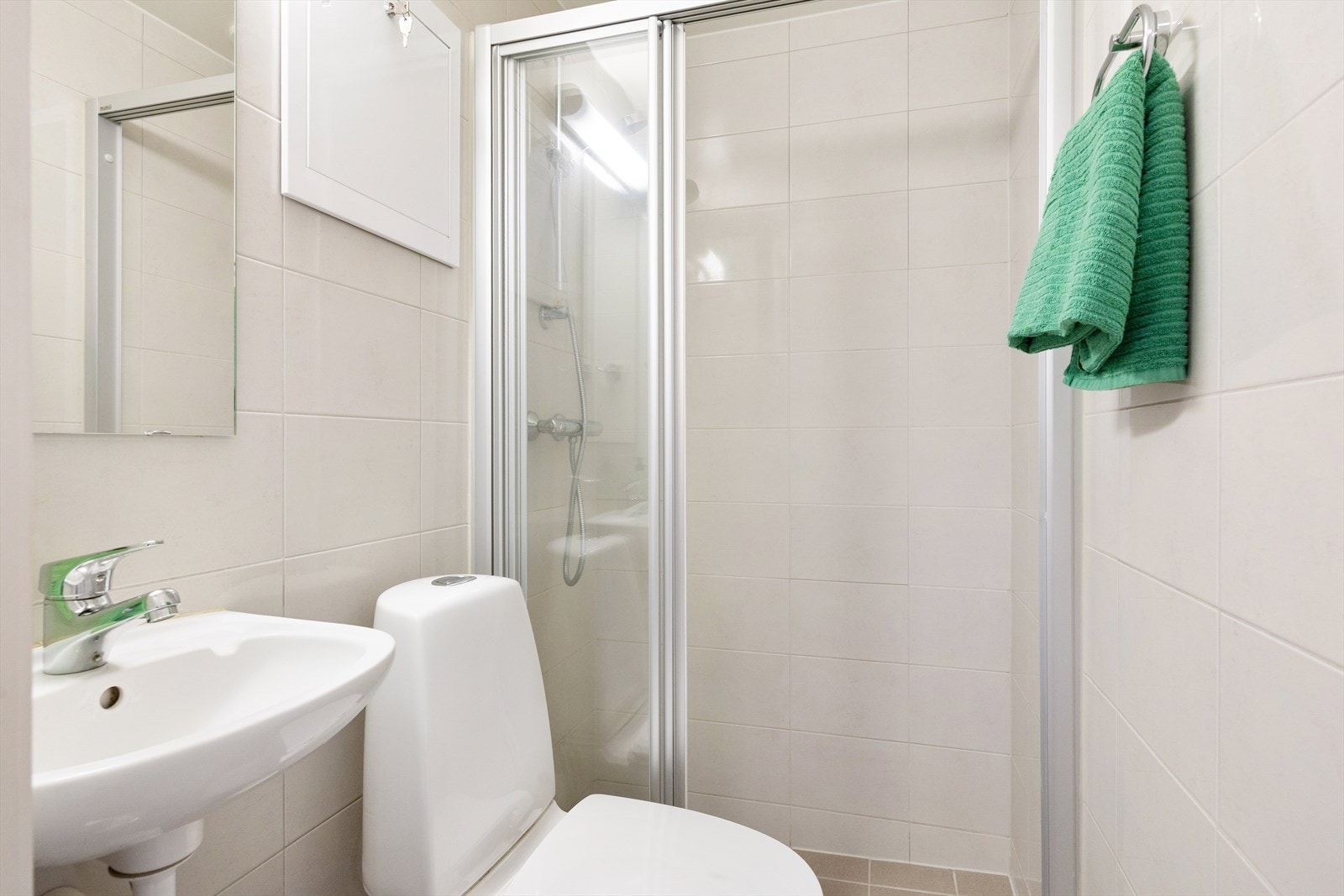 Badet er innredet med WC, dusjplass med vegger, servant med ettgreps blandebatteri og opplegg for vaskemaskin. Galleribilde