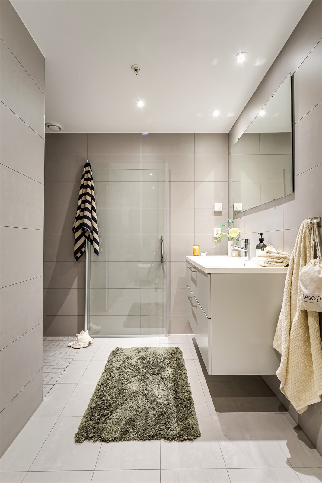 Baderommet er innredet med servant i skuffeseksjon, veggmontert toalett og dusjhjørne. Galleribilde