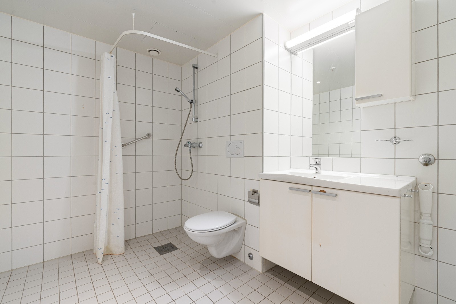 Flislagt bad, varme i gulv og lagring i skuff og skap.